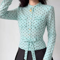 Lifestyle model shot light blue brown polka dot stand collar long sleeve shirt, dual chest patch pockets, self fabric waist tie belt, fitted cropped silhouette