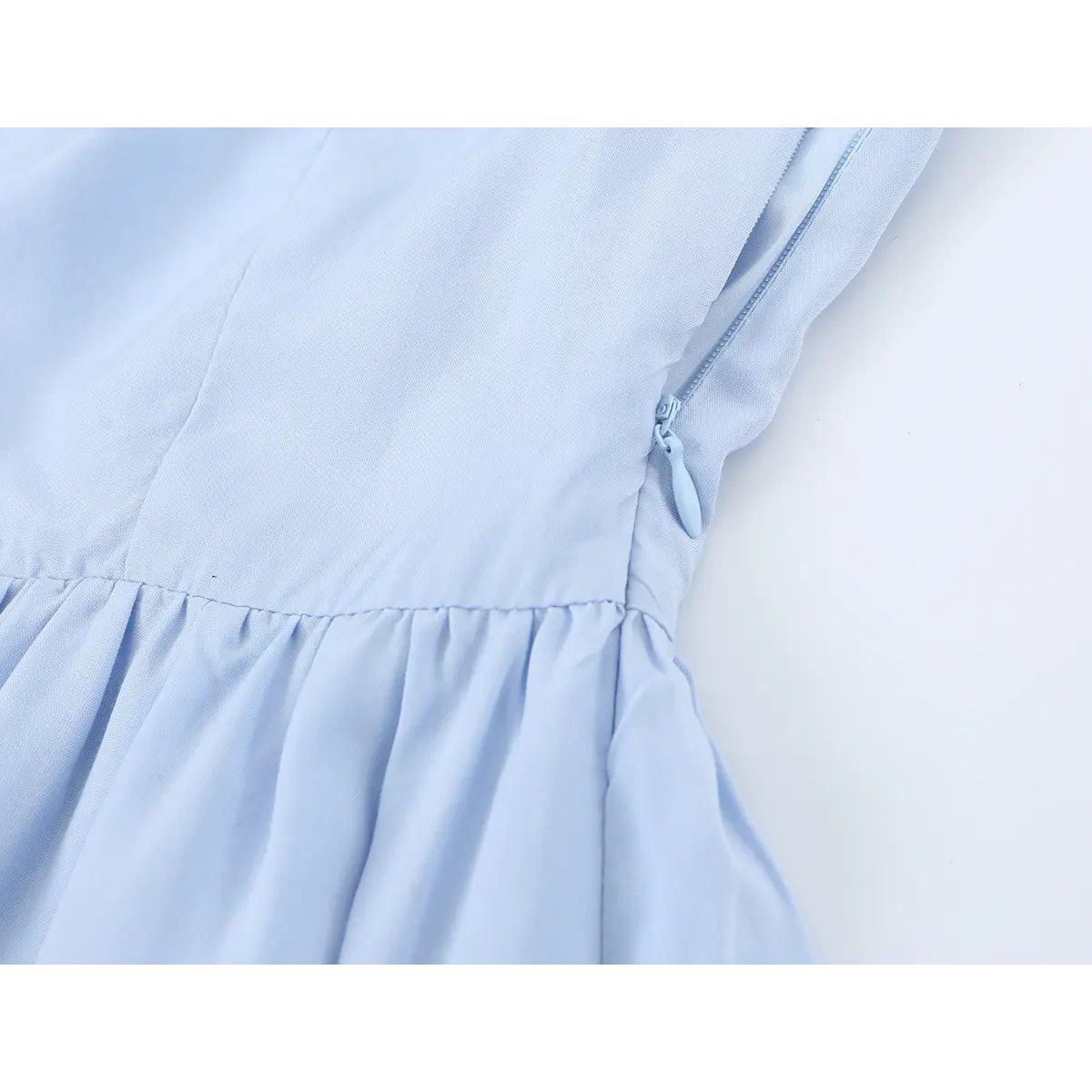 Close-up of the waist seam and gathered skirt detail on the light blue cami dress