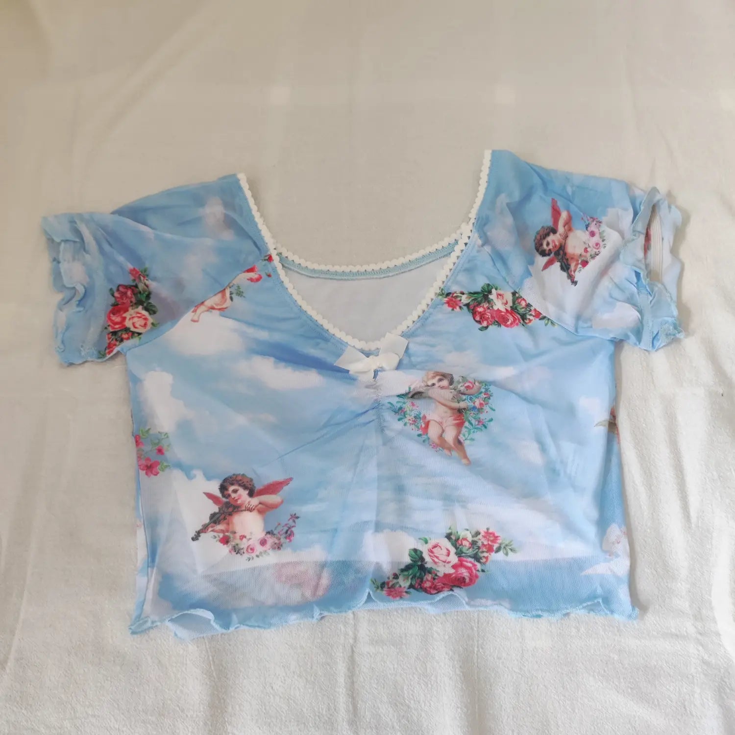 Flat lay front view light blue short sleeve mesh crop top angel rose print v‑neck with small white bow