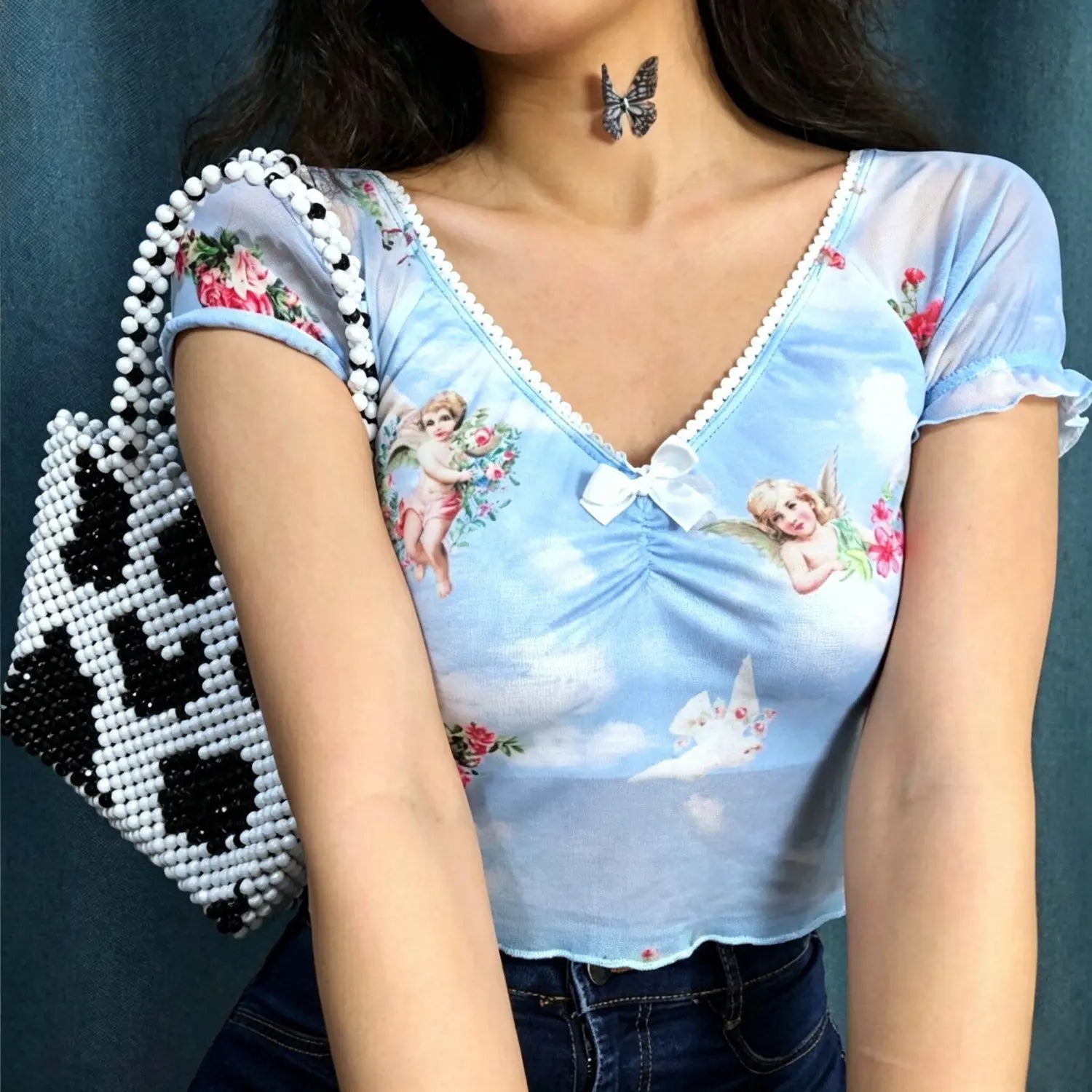 Model torso close‑up light blue sheer mesh crop top with angel print v‑neck bow detail
