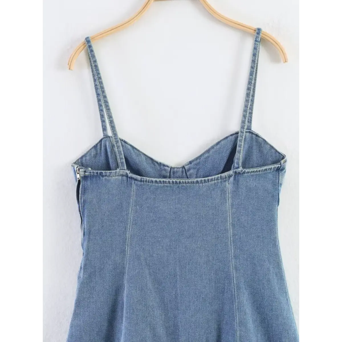 Close-up of the back silhouette and seam details on the light blue denim cami dress