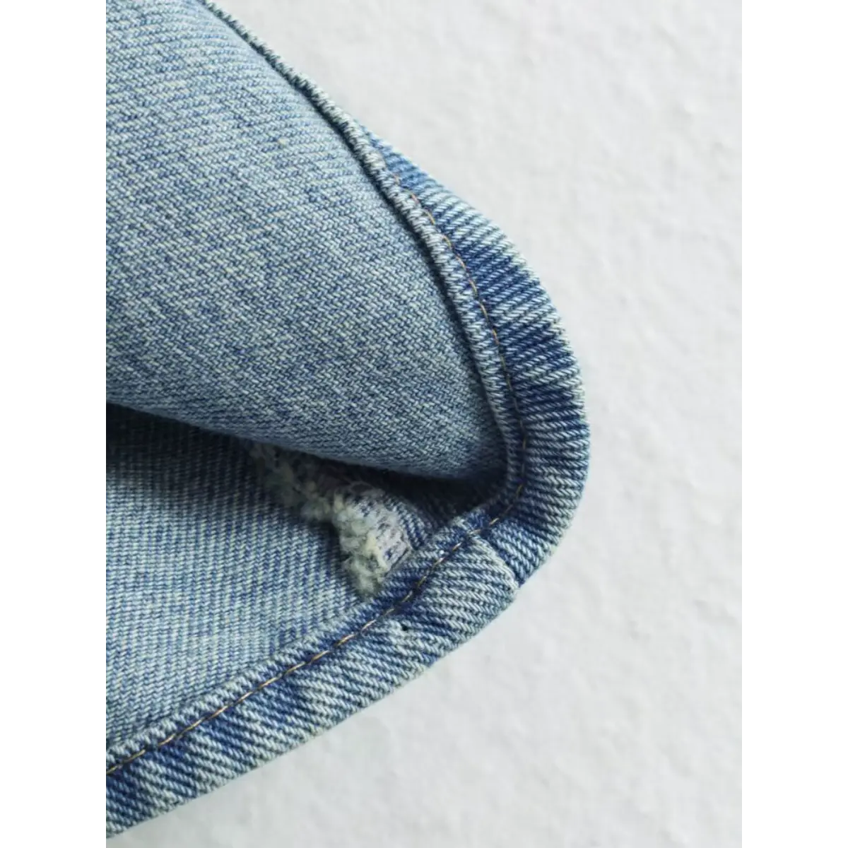 Close-up of the flared hem and denim fabric texture on the light blue cami dress