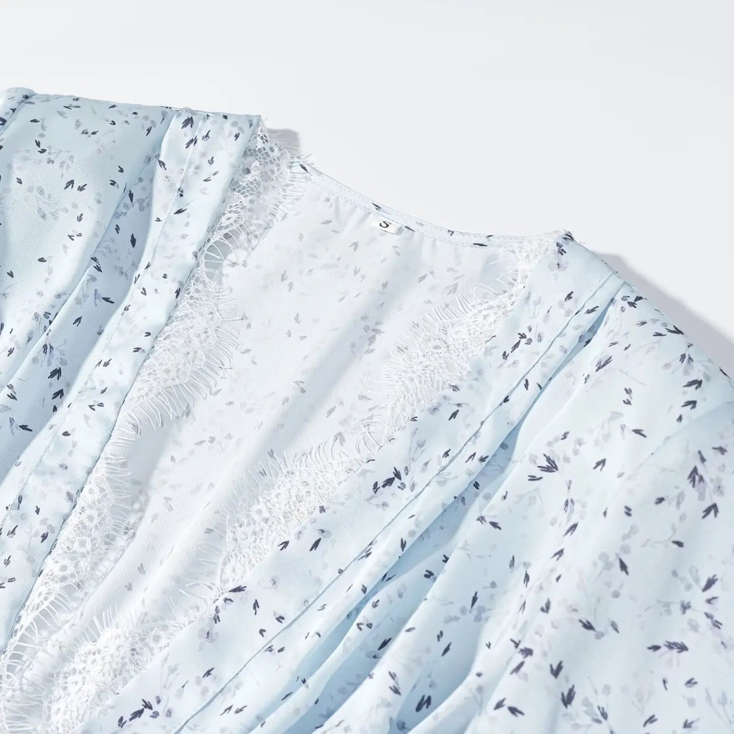 Close‑up v‑neck white eyelash lace trim and inner label detail of light blue ditsy floral maxi dress