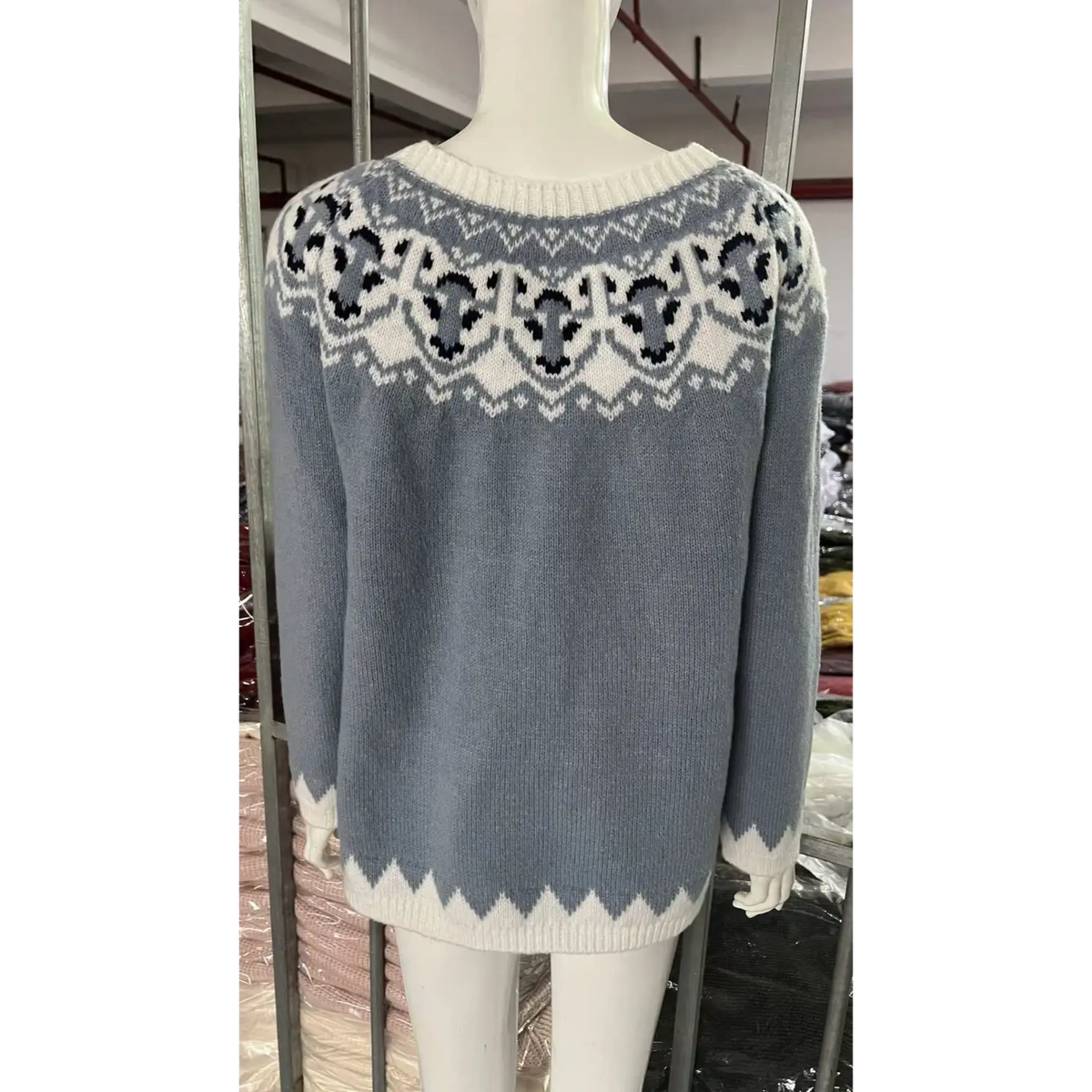 Back view of white mannequin showing light blue fairisle jacquard sweater, retro geometric knit pattern, factory stock background