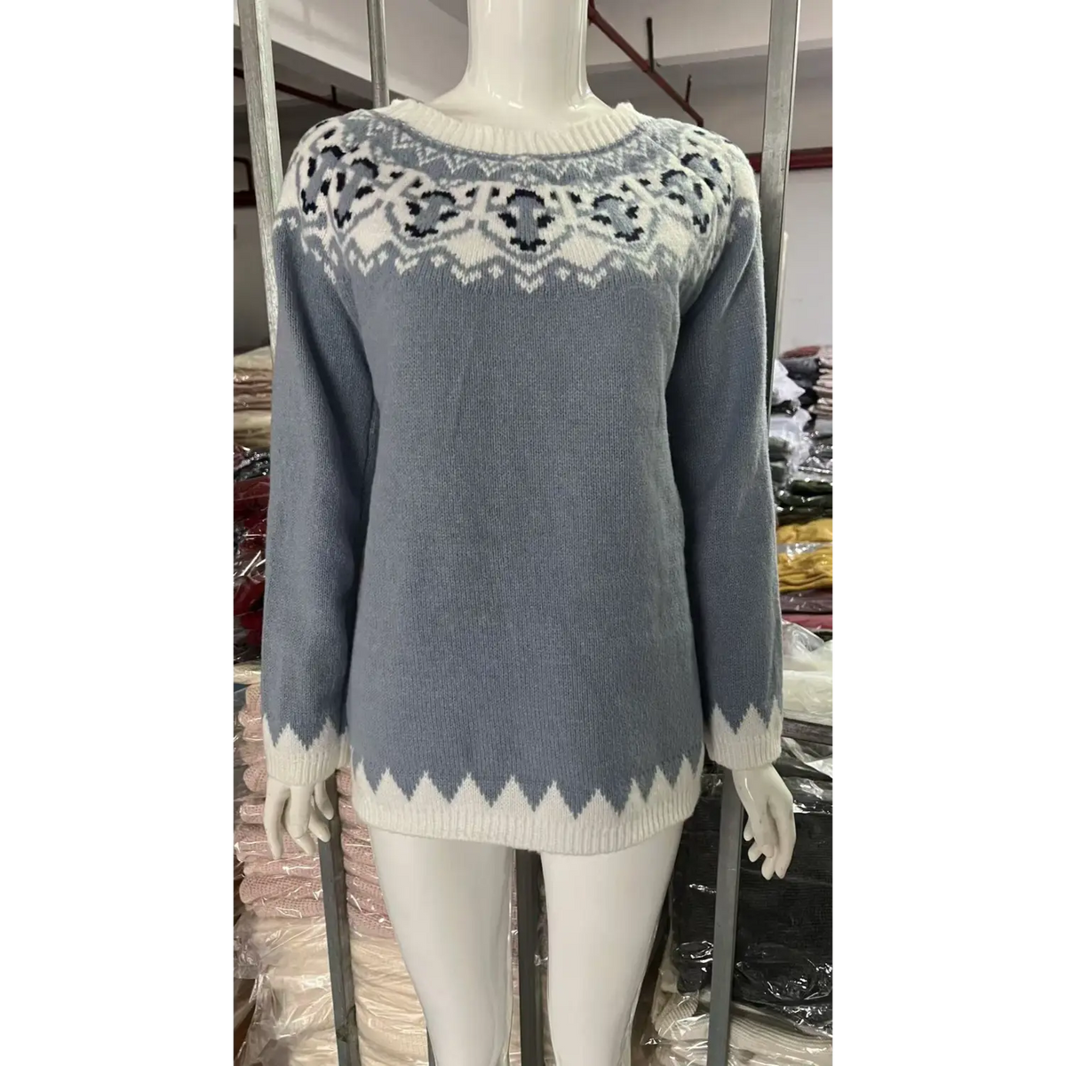 Front view of white mannequin dressed in light blue fairisle jacquard sweater, retro geometric knit pattern, factory background