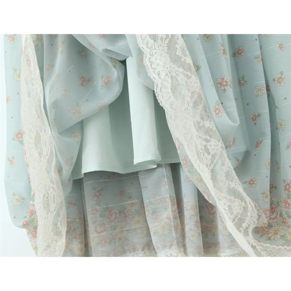 Close-up of the layered skirt hem and lace trim on the light blue floral midi dress