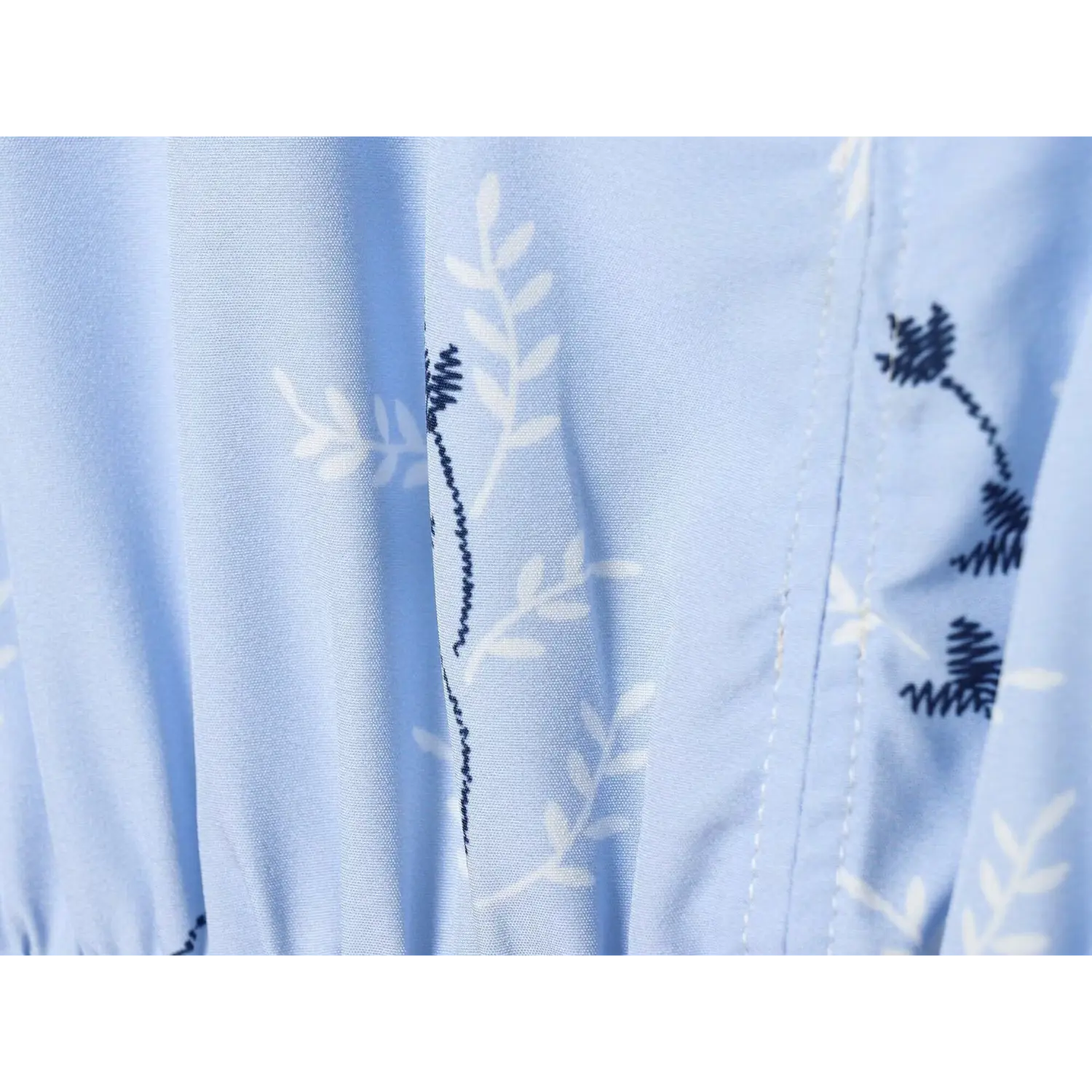 Macro texture shot of light blue floral printed woven fabric, showing print and weave detail