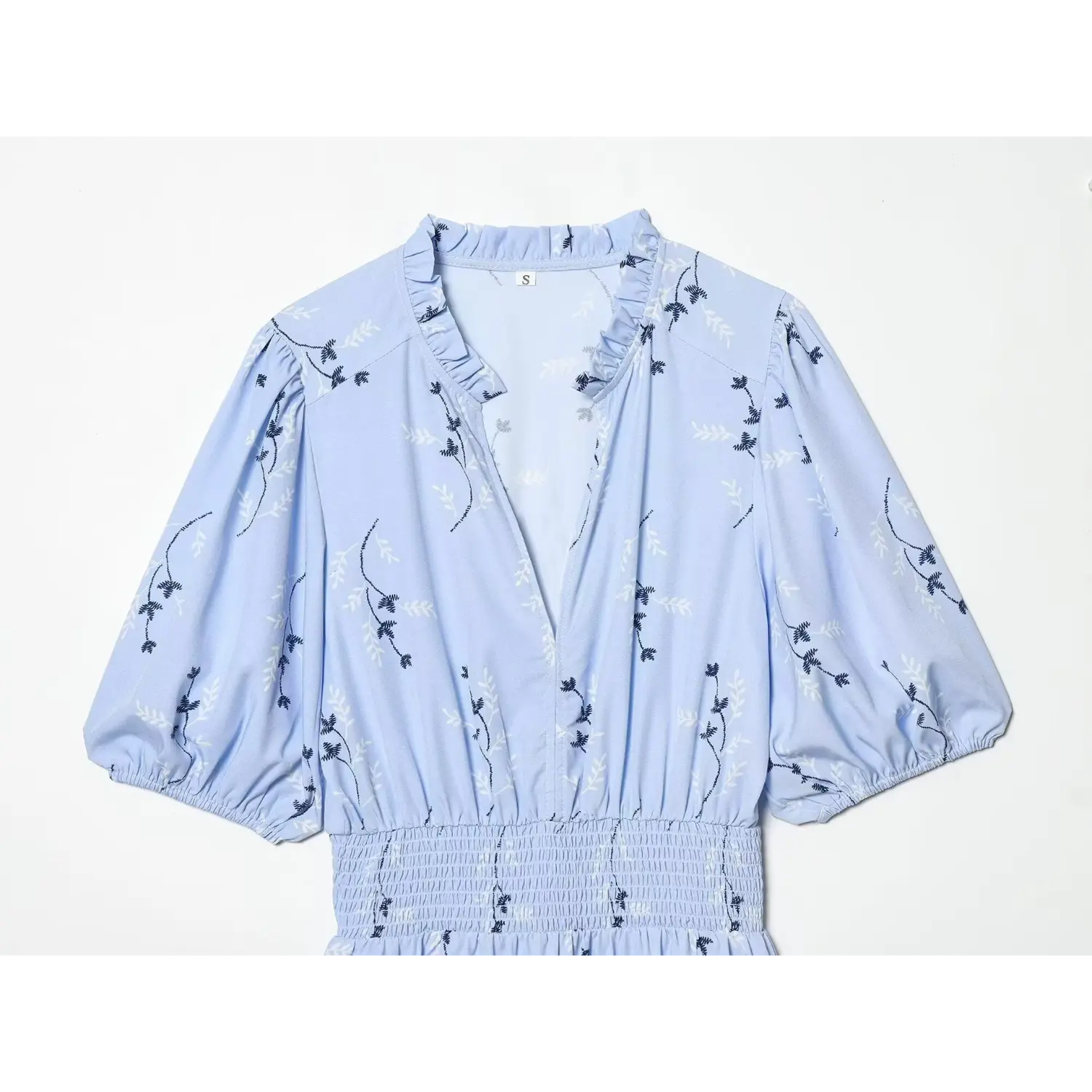 Close‑up upper portion of light blue floral dress, ruffle v‑neck, puff sleeves and smocked waist detail