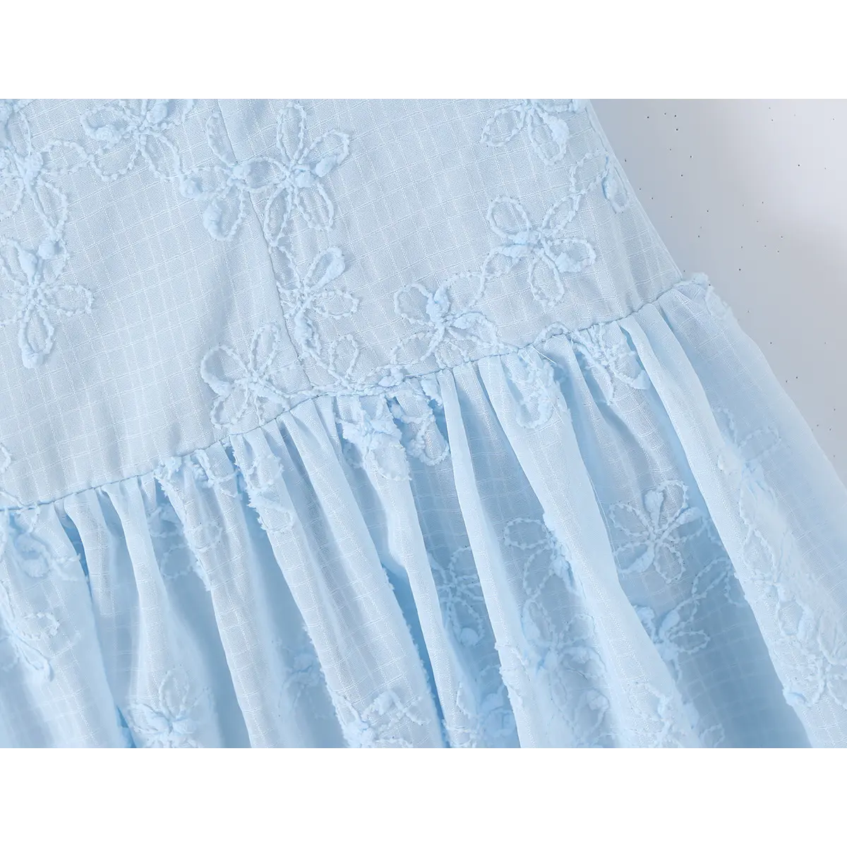 Close-up of the waist seam where the bodice meets the skirt on a light blue spaghetti strap dress.