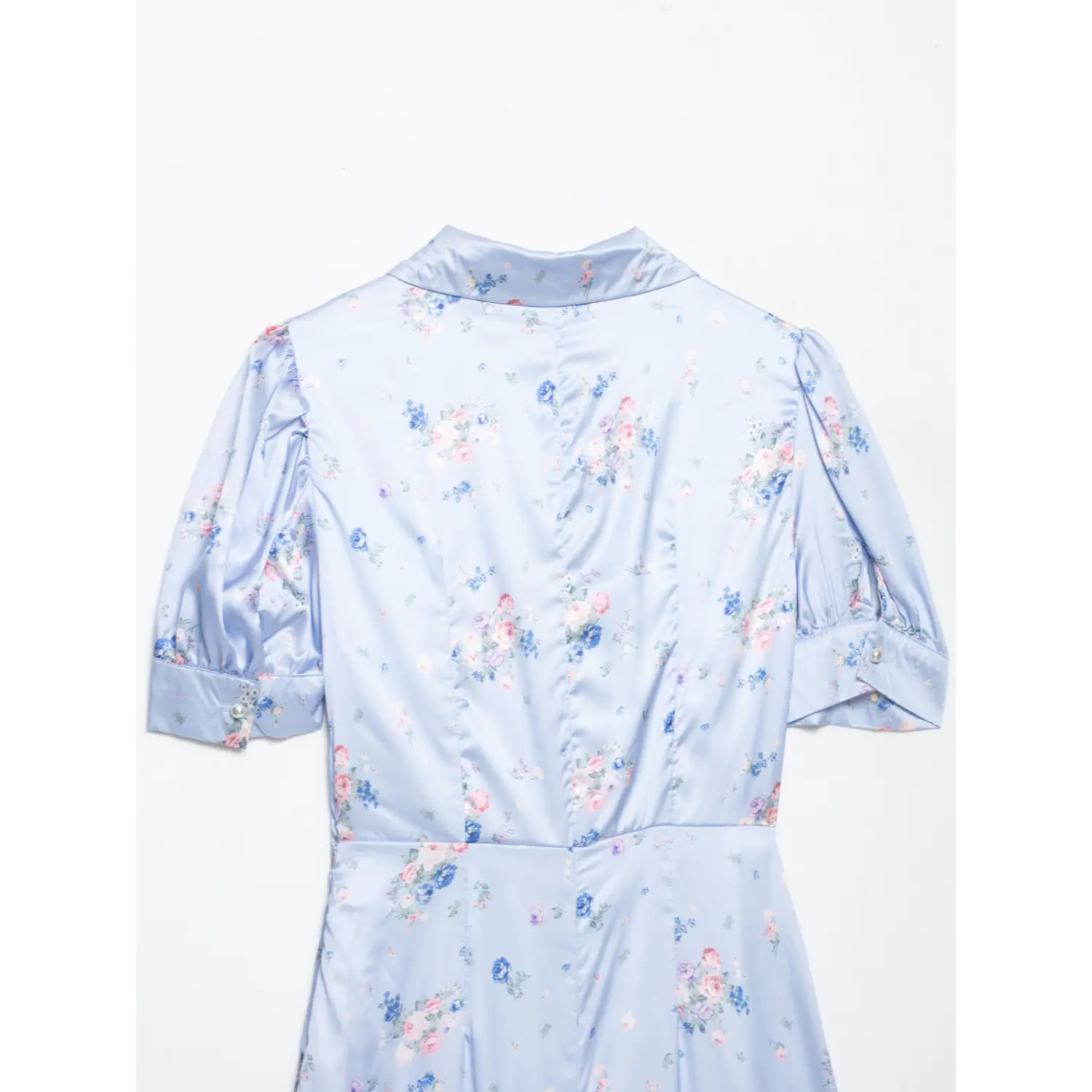 Close-up of the back bodice of light blue satin floral maxi dress, princess seam design, puff short sleeves with pearl cuff button
