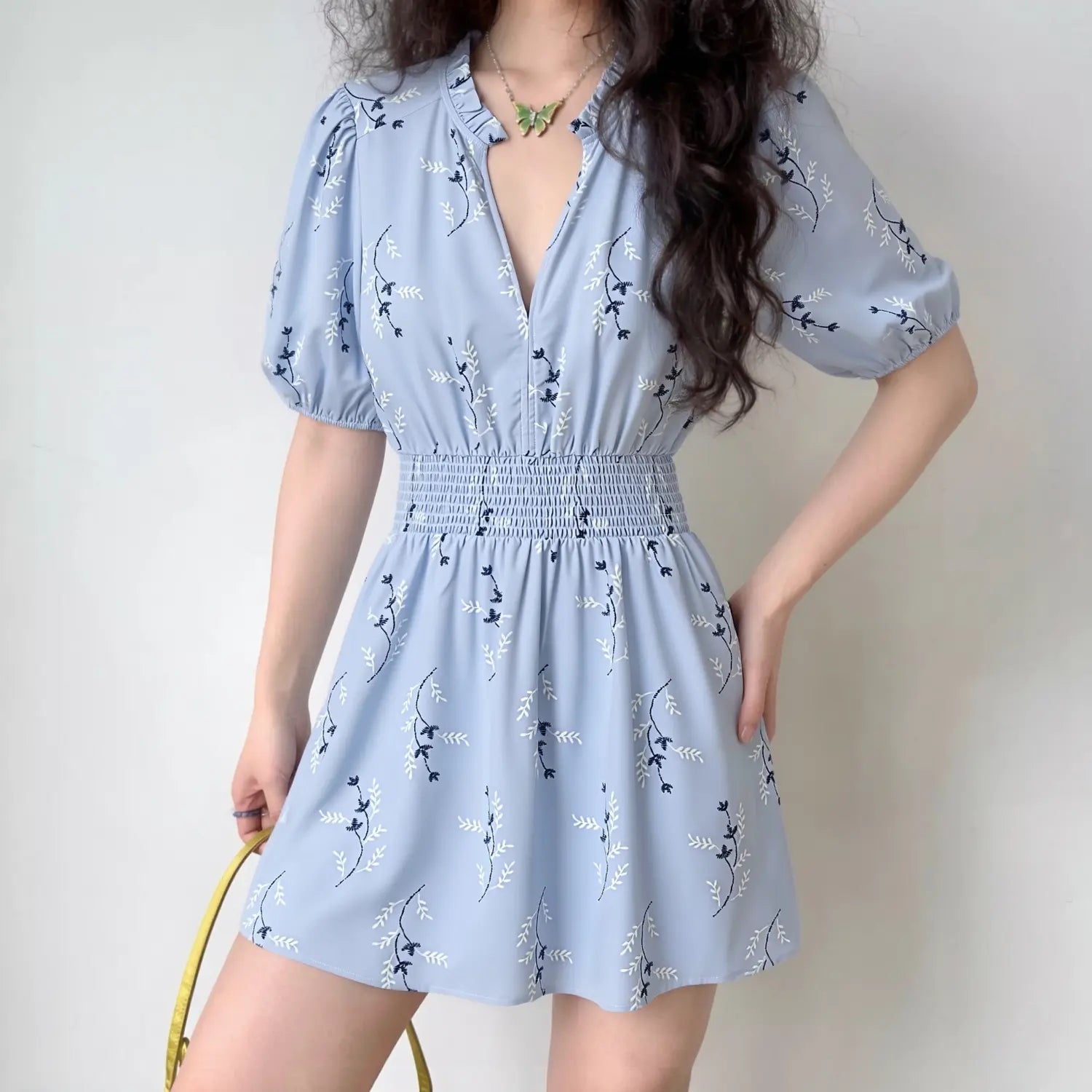 Female model wearing light blue floral print mini dress, front full body view, smocked waist, puff short sleeves