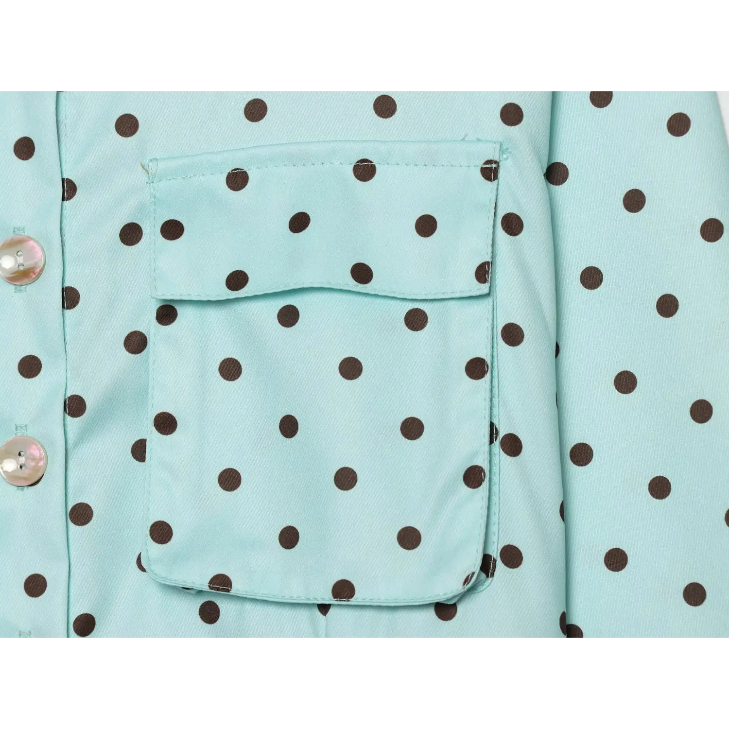 Macro view rectangular chest patch pocket, clean topstitch edges, light blue brown polka dot woven fabric