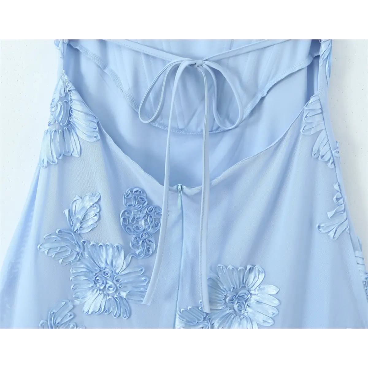Close-up of the back of a light blue gown, featuring a lace-up corset tie and invisible center zipper.