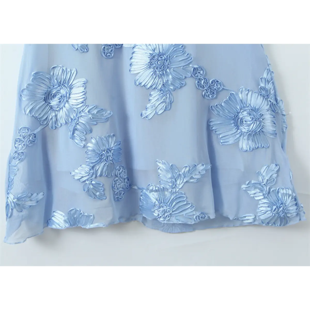 Close-up of the mermaid hem of a light blue gown, showcasing the 3D floral embroidery and scalloped edge.