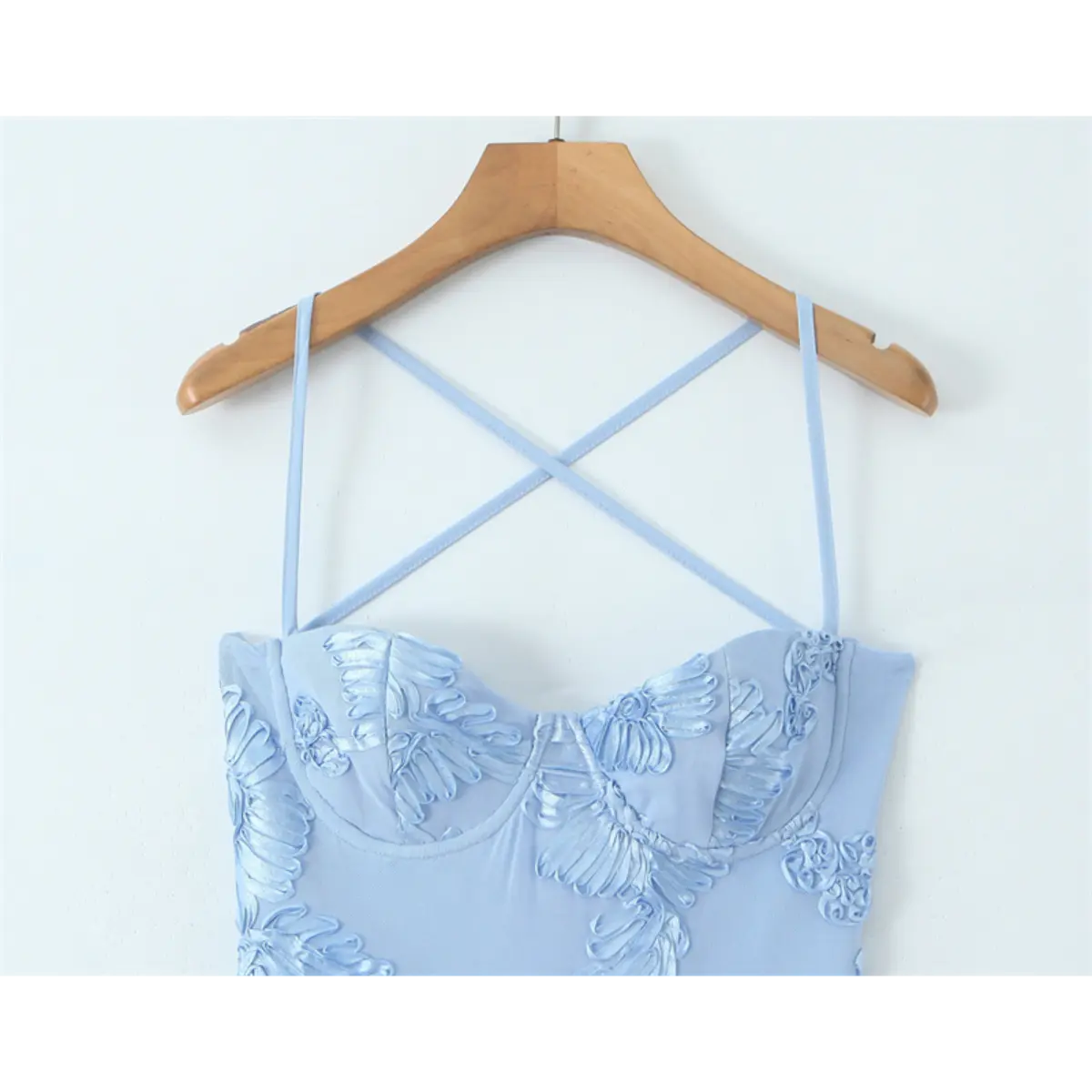 Close-up of the sweetheart bustier on a light blue gown, showing the crisscross spaghetti straps and floral embroidery.