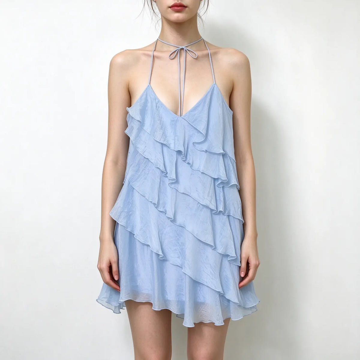 Model wearing light blue halter tie neck tiered chiffon mini dress with deep v neck, plain white background