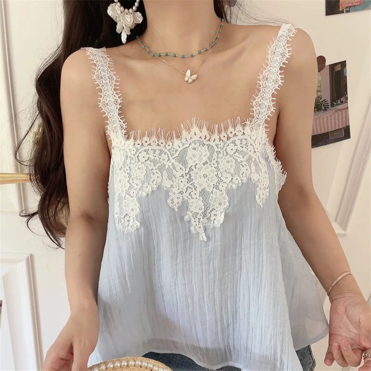 Close-up of the light blue cami top, highlighting the delicate floral lace and textured fabric.