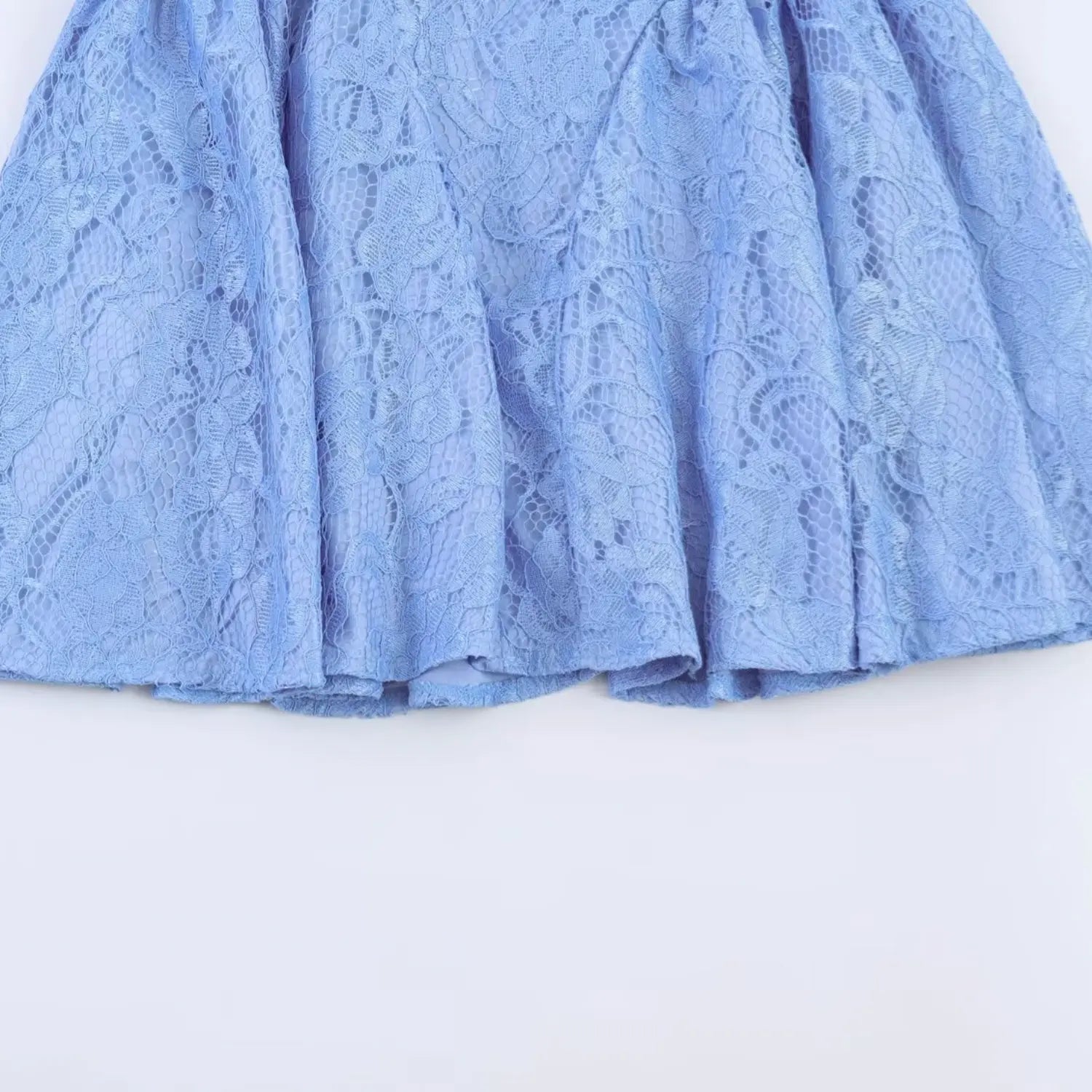 Macro shot of multi-panel flare skirt hem, textured floral lace material close up