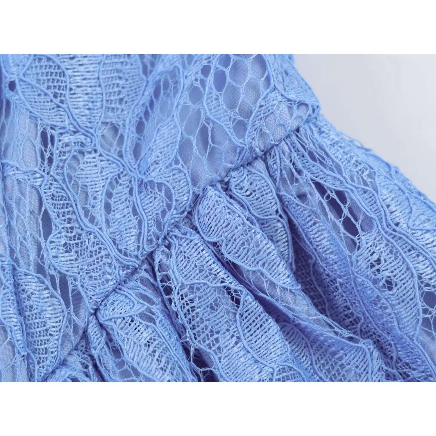 Detailed closeup of fitted waist seam and gathered lace fabric on fit-and-flare dress