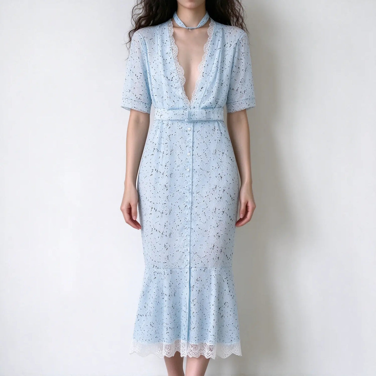 Model in light blue floral lace maxi dress, deep v neckline with delicate lace trim, short cuffed sleeves, self fabric waist belt, front button placket, mermaid maxi hem with lace trim, plain white background
