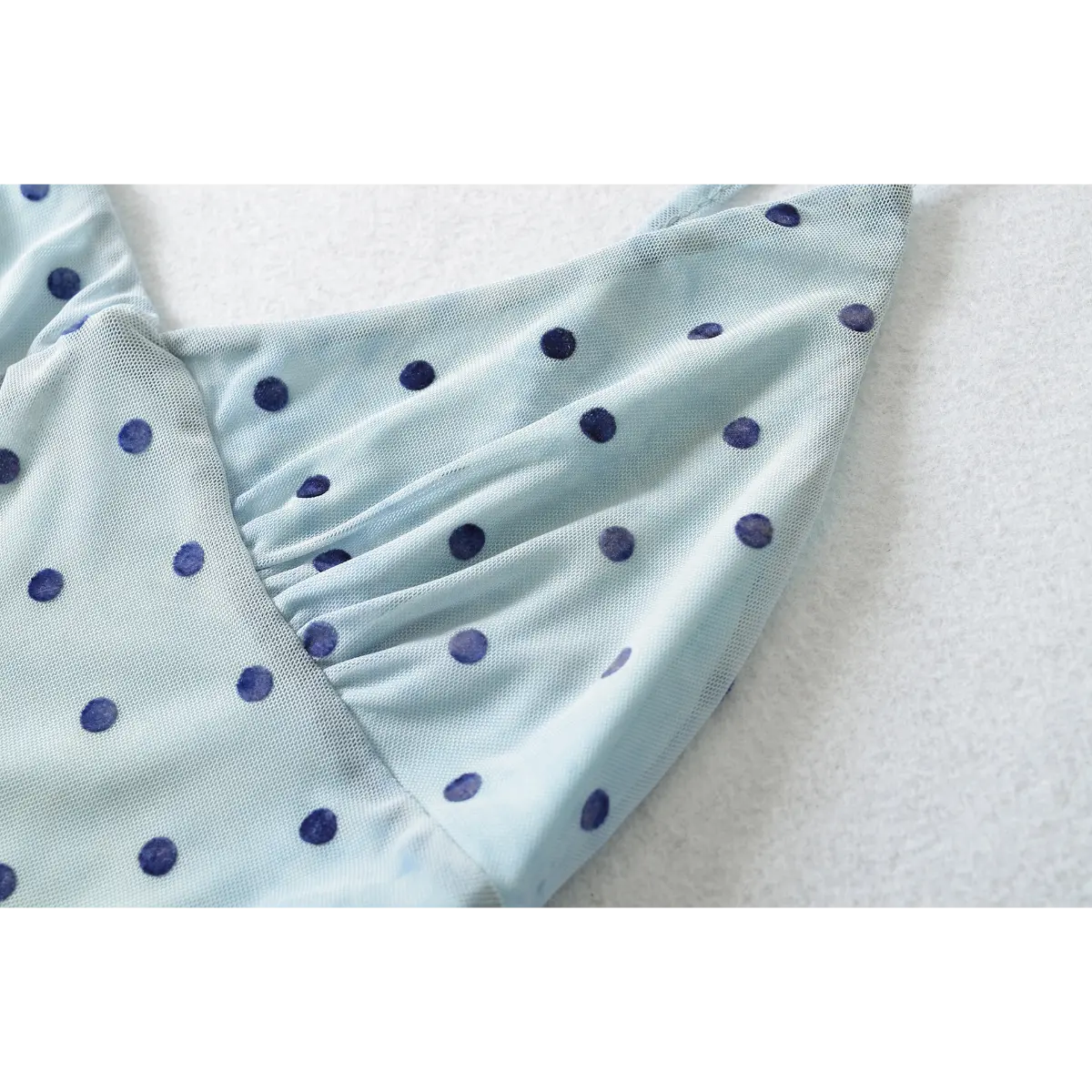 Close-up of the V-neckline and gathered bust, showing the sheer mesh fabric and watercolor-style polka dot print.
