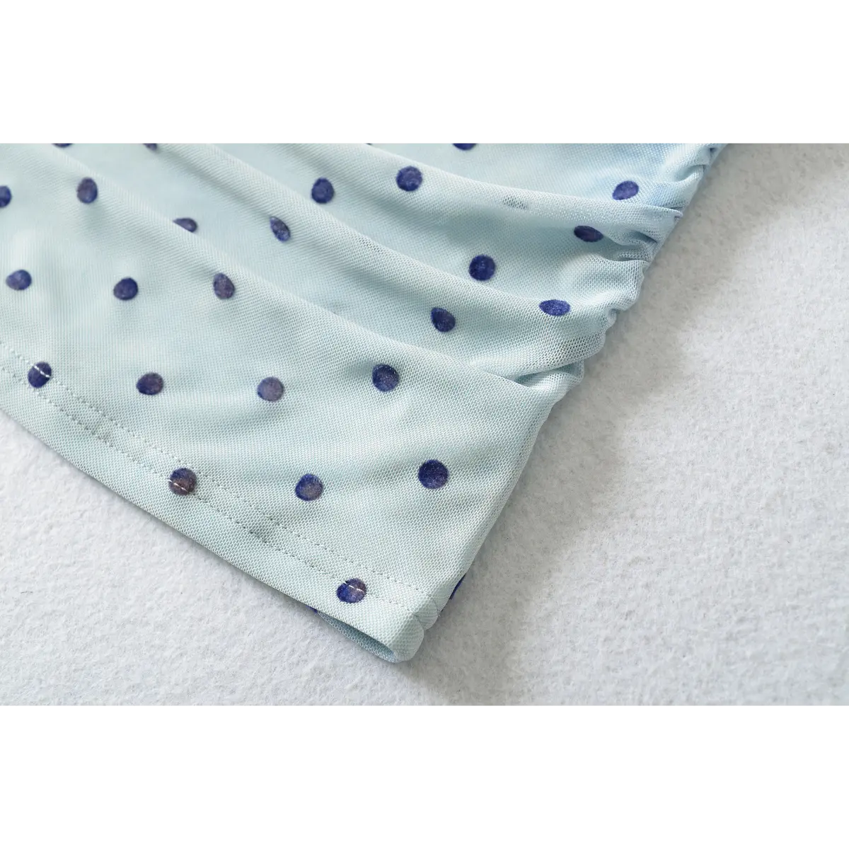 Close-up of the clean-finished hem, featuring the overlock stitching and stretch mesh fabric.