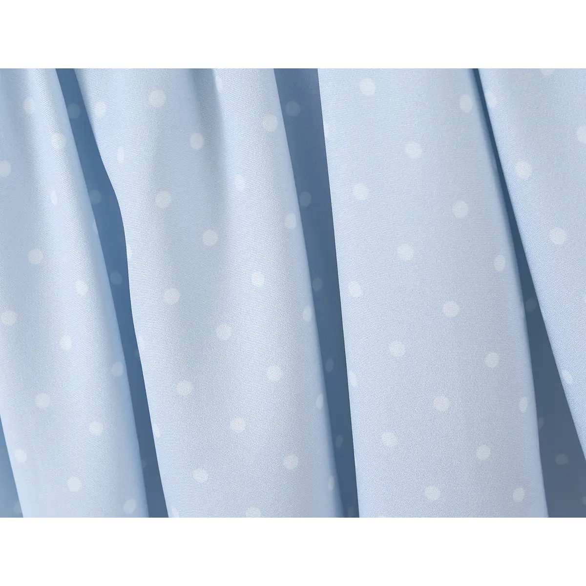 Close-up of the fabric texture of a light blue polka dot dress, showing the dot pattern and smooth material.