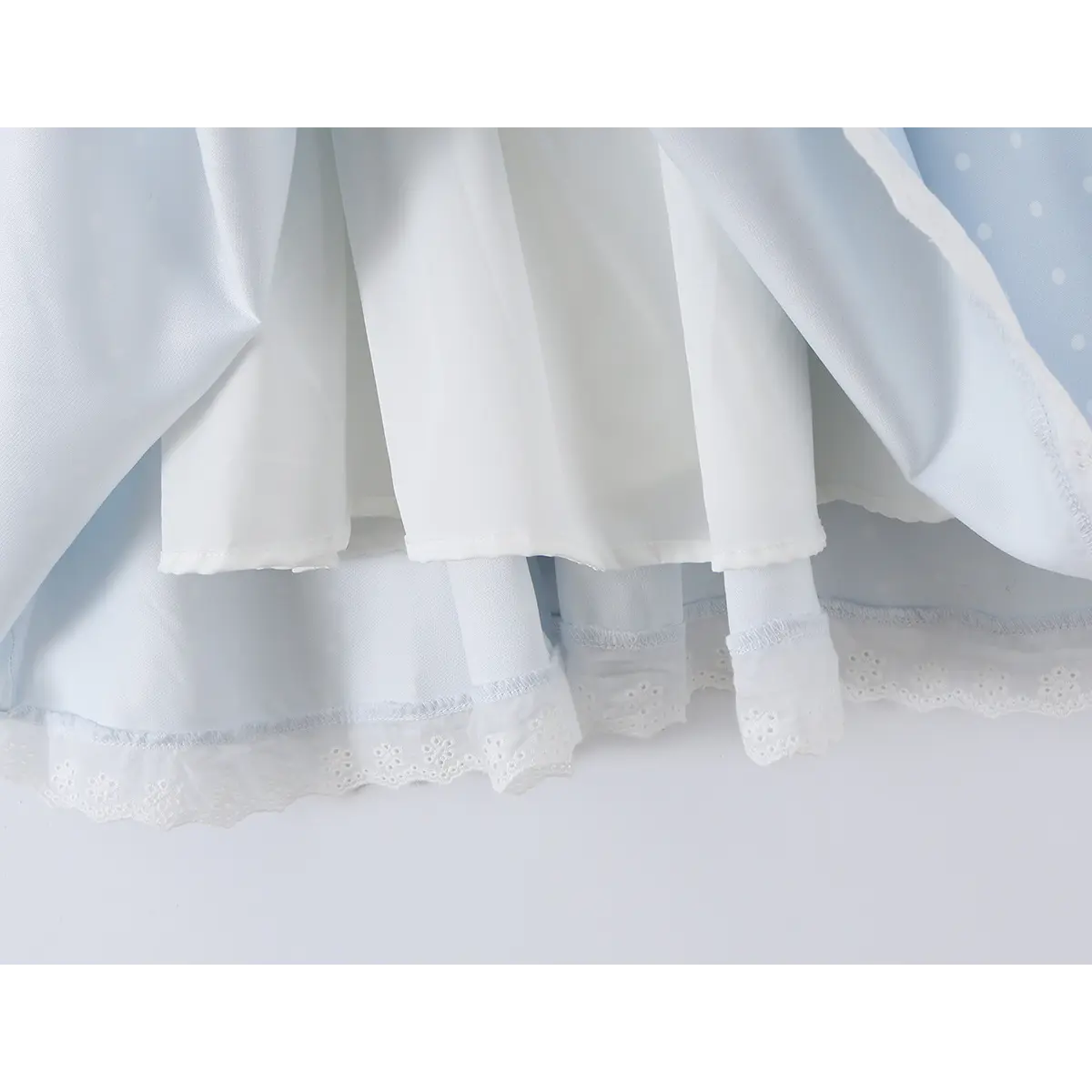 Close-up of the inner lining and lace-trimmed hem on a light blue polka dot corset-style dress.