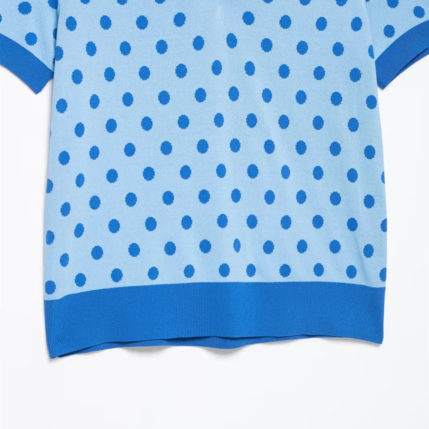 Close-up of the polka dot knit texture on the body of the light blue polo top