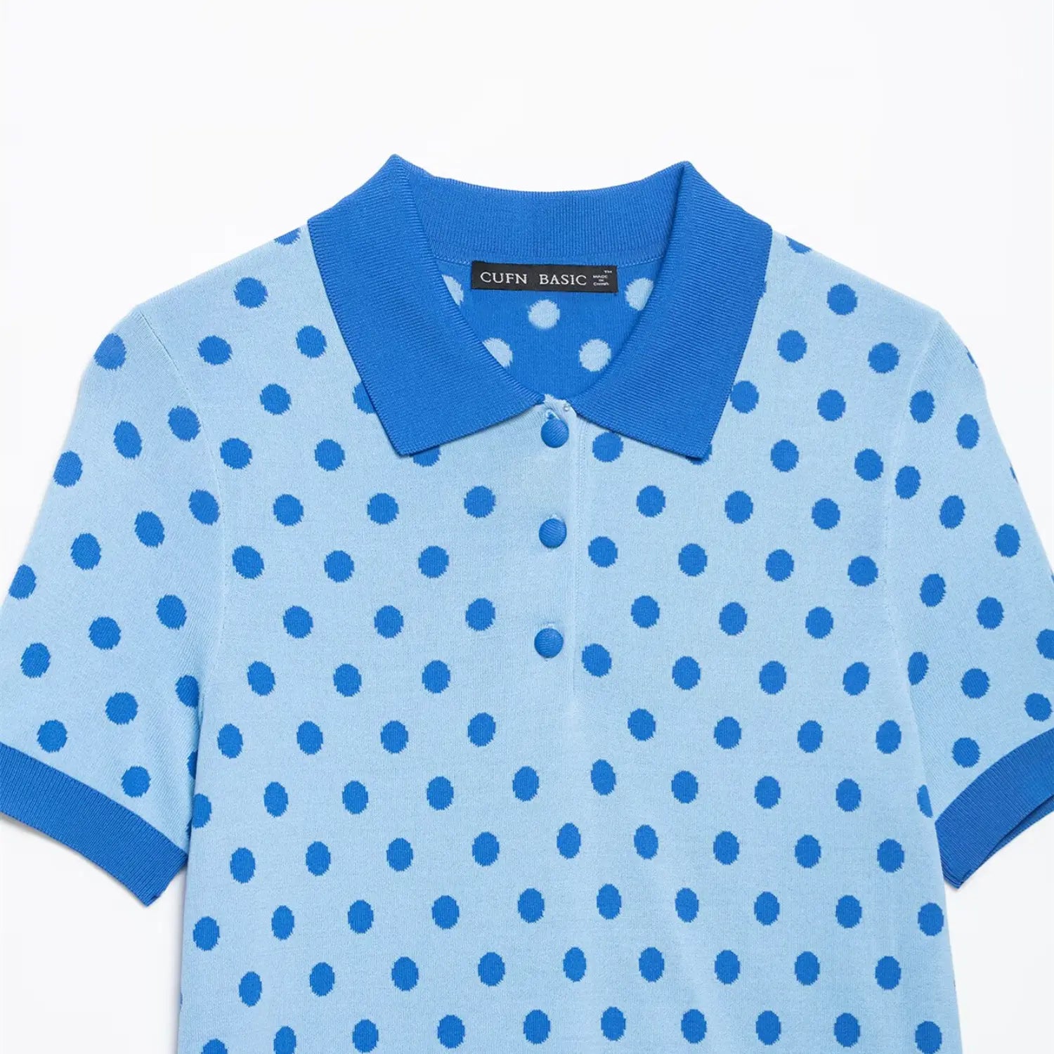 Close-up of the polo collar, three-button placket, and polka dot pattern on the light blue knit top