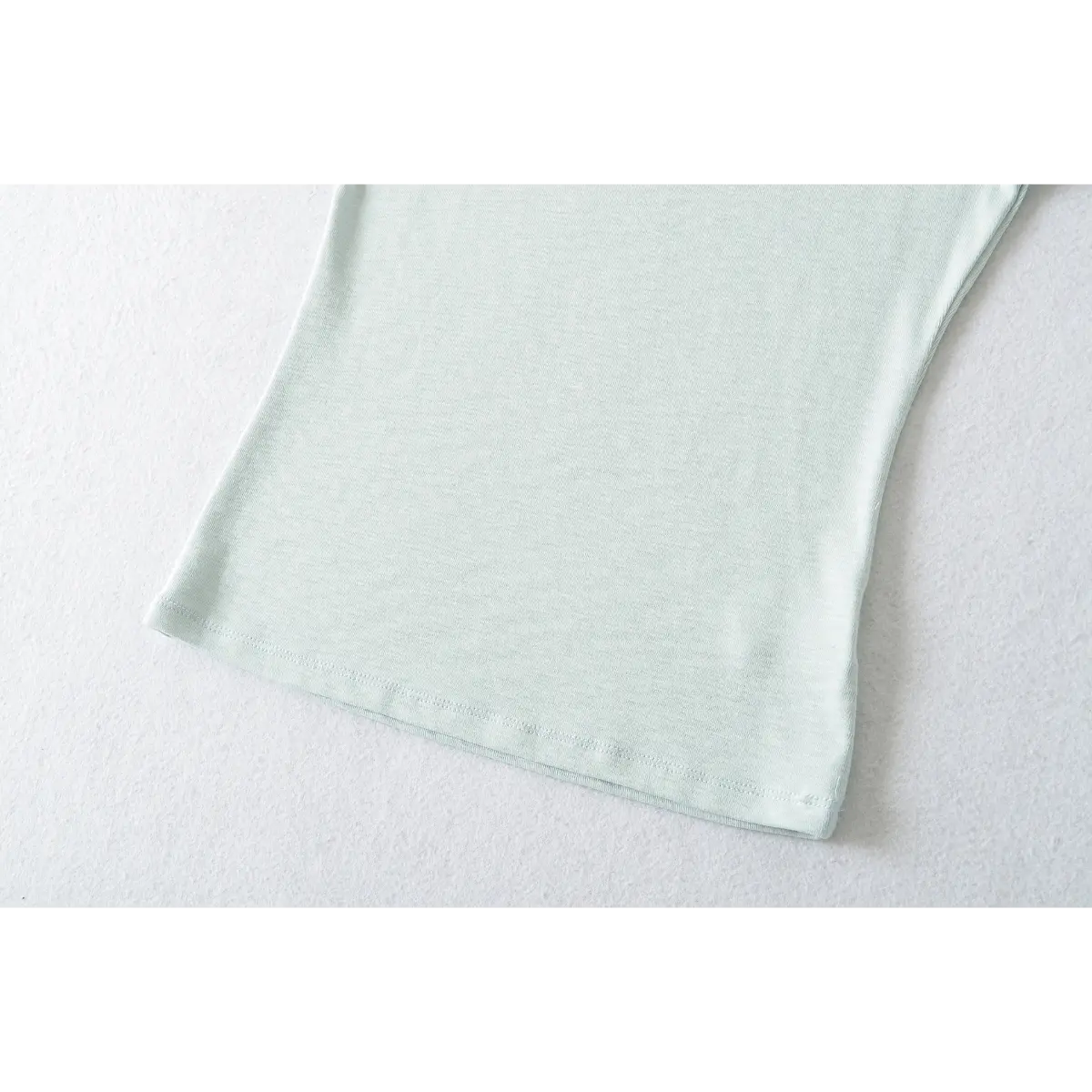 Close-up of the double-stitched hem on the light blue ribbed crew-neck t-shirt