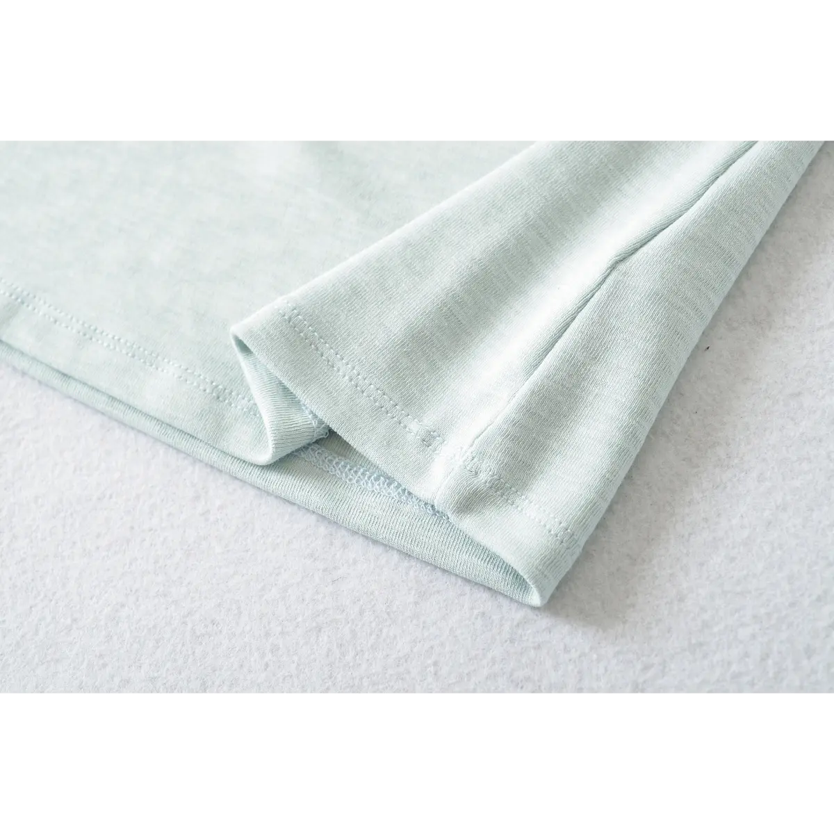 Close-up of the double-stitched cuff on the light blue ribbed crew-neck t-shirt
