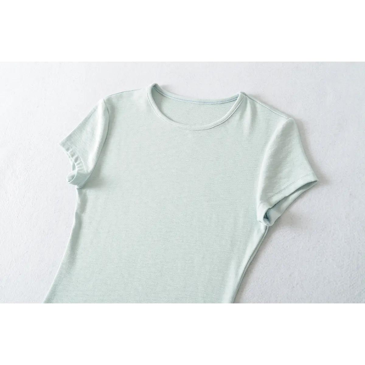 Partial front view of light blue ribbed crew-neck t-shirt, showing neckline and shoulder seams