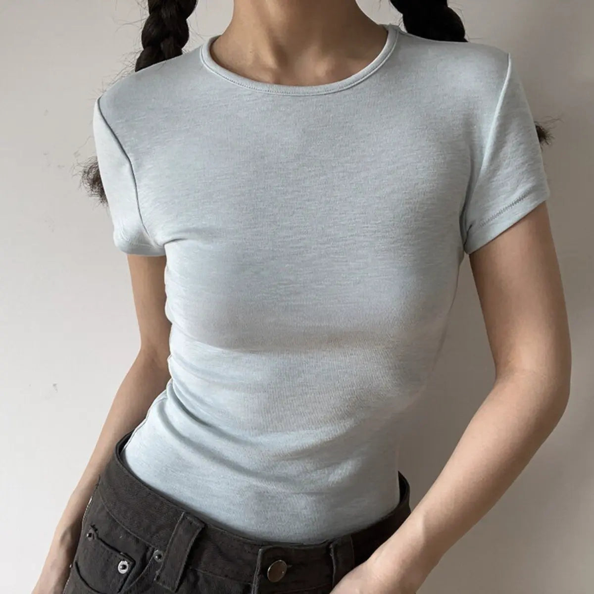 Lifestyle shot of form-fitting light blue ribbed crew-neck short-sleeve t-shirt, tucked into jeans