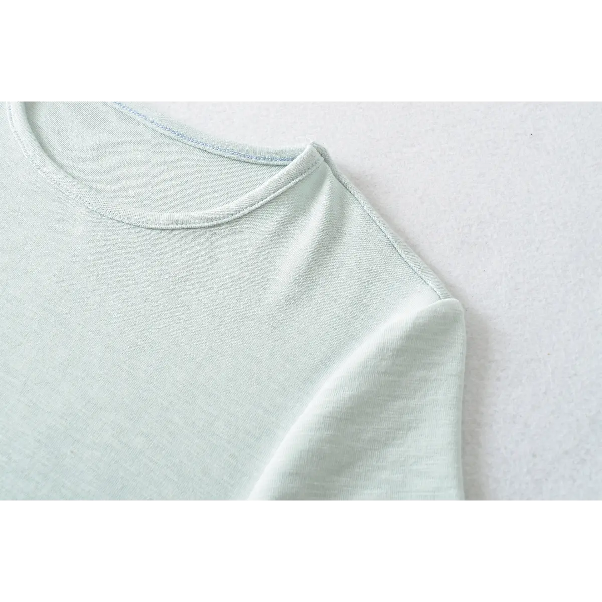 Close-up of the ribbed crew neckline stitching on the light blue t-shirt