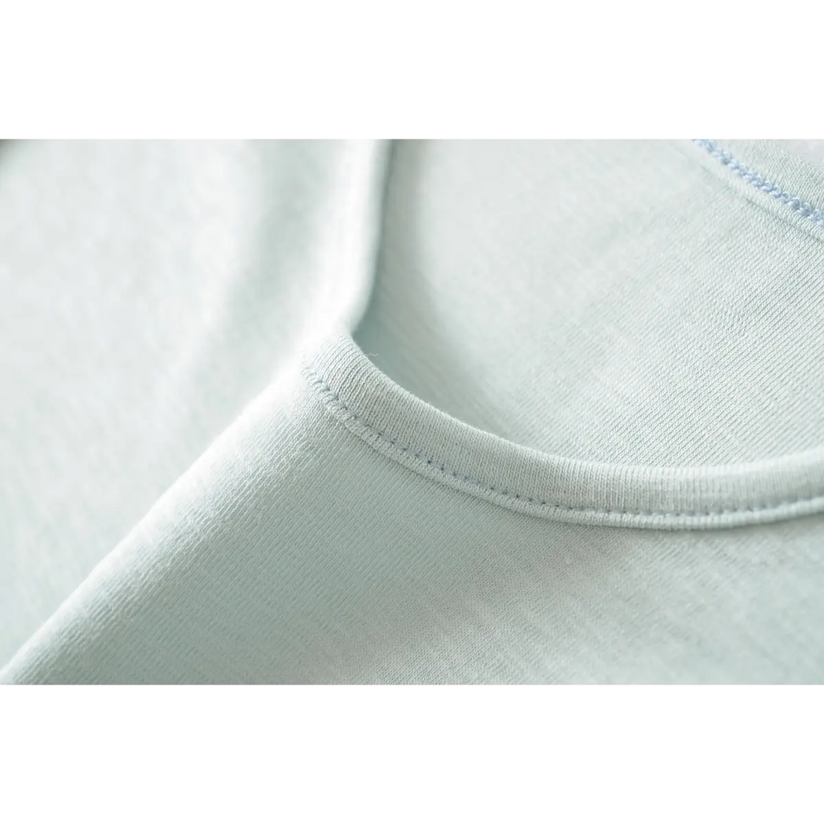 Close-up of the ribbed crew neckline stitching on the light blue t-shirt