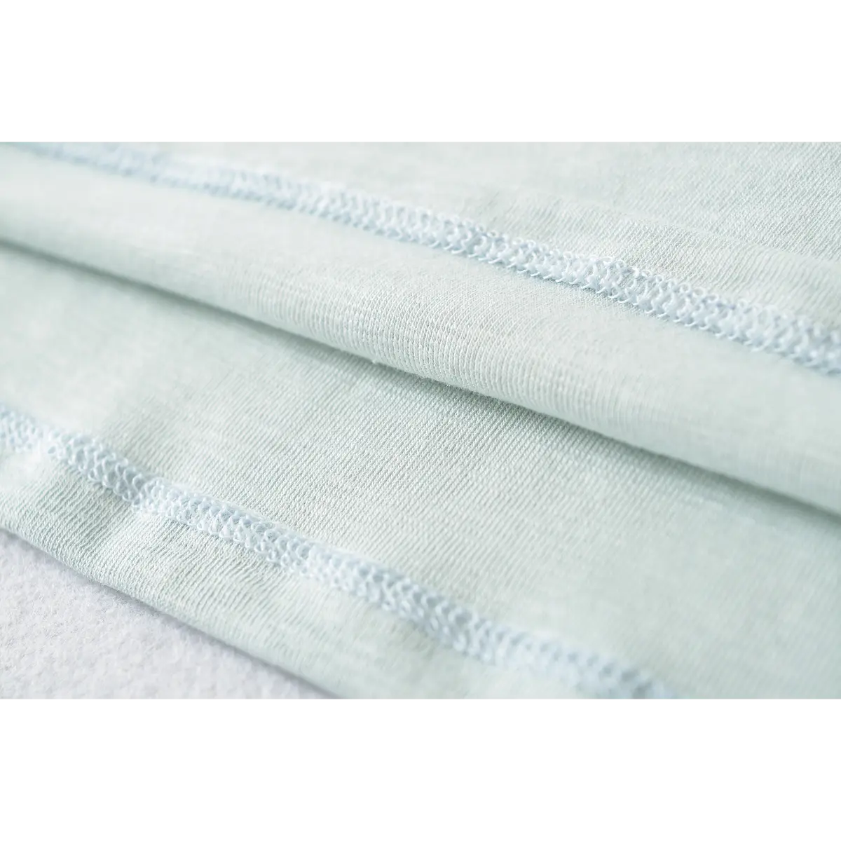 Close-up of the coverstitch seams on the light blue ribbed t-shirt fabric