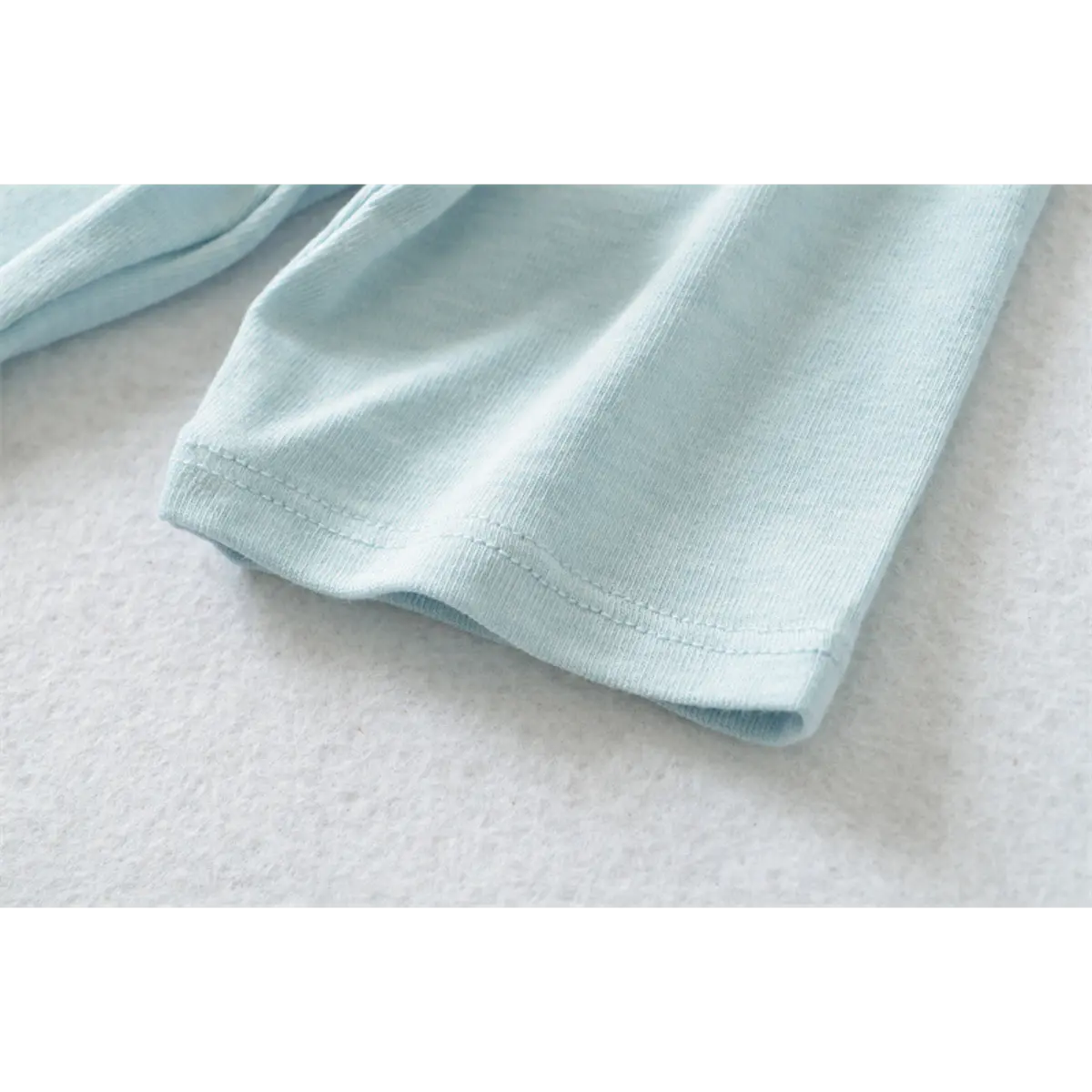 Close-up of the stitching on the cuff of the light blue ribbed half-turtleneck top