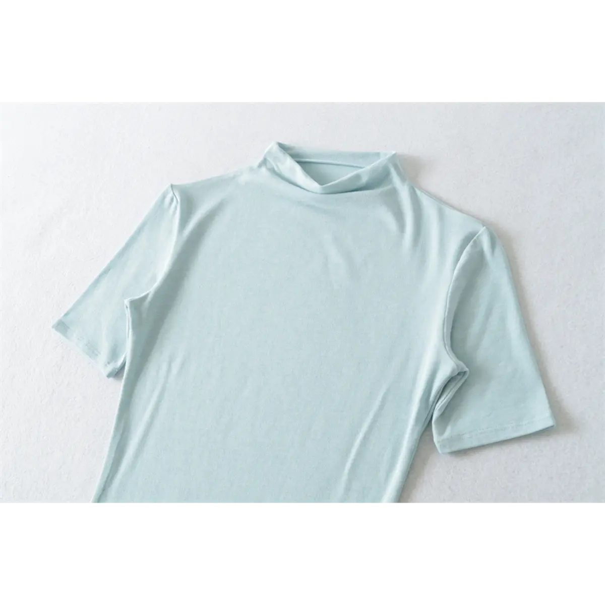 Partial front view of light blue ribbed half-turtleneck top, showing neckline and shoulder seams