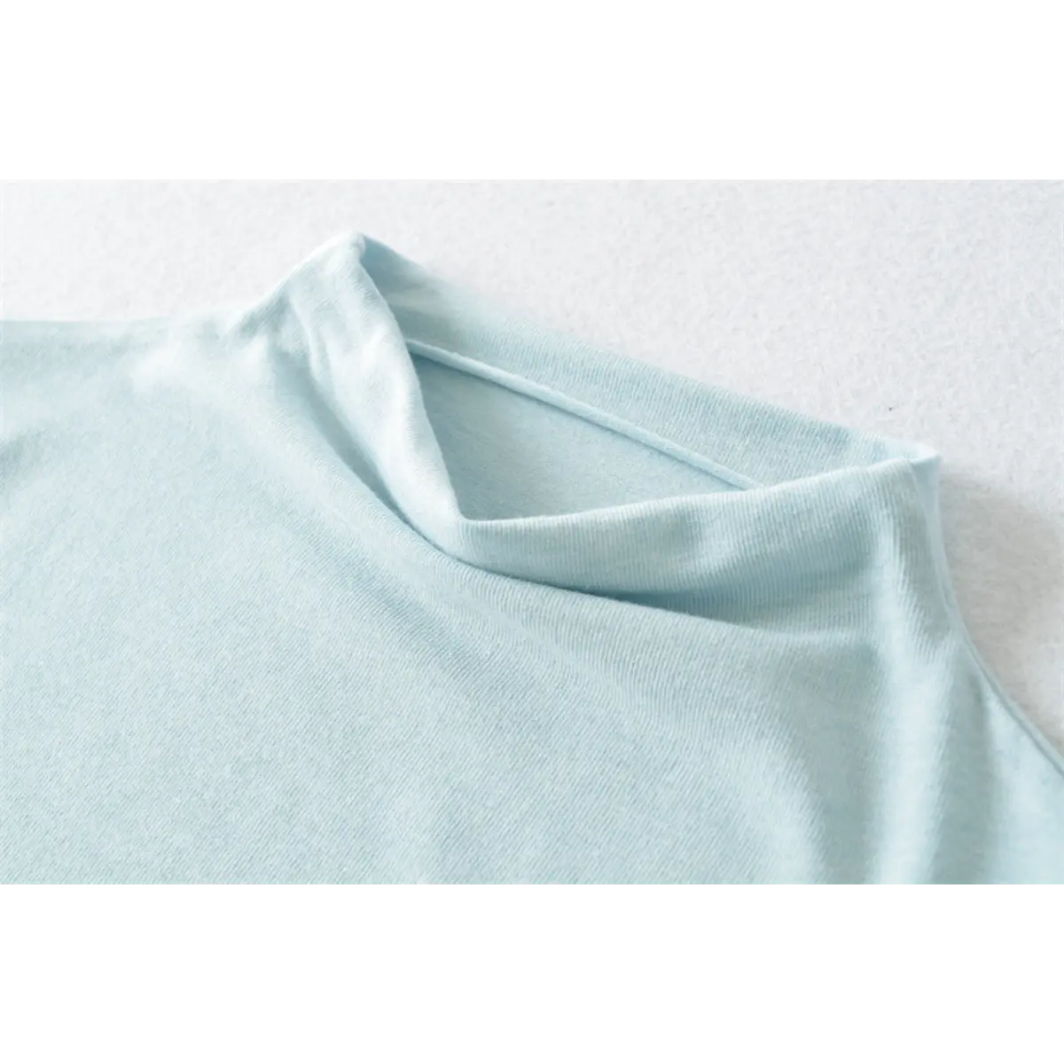 Close-up of the half-turtleneck neckline on the light blue ribbed top, showing fabric texture and stitching