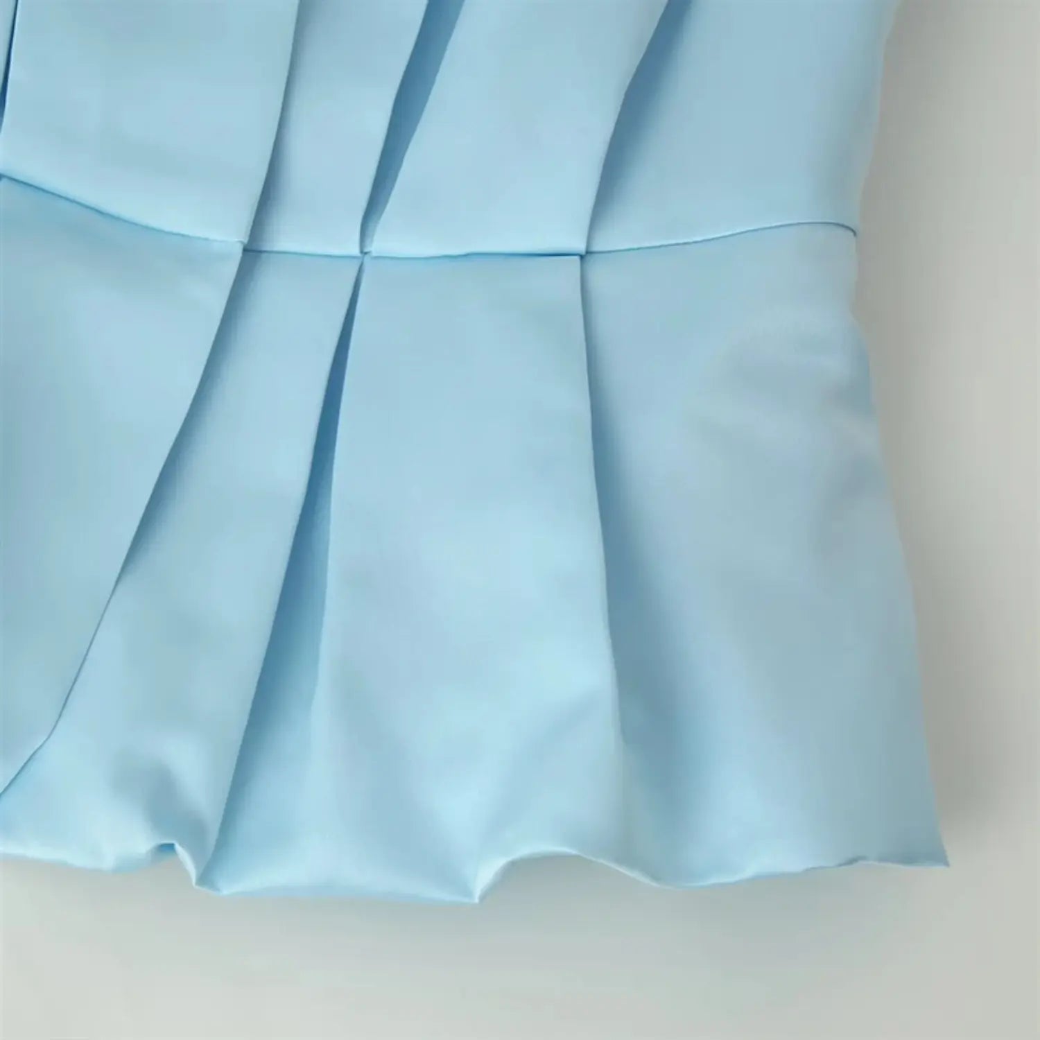 Waist to peplum hem transition macro, multiple vertical waist pleats, flared ruffle hem satin panel stitching