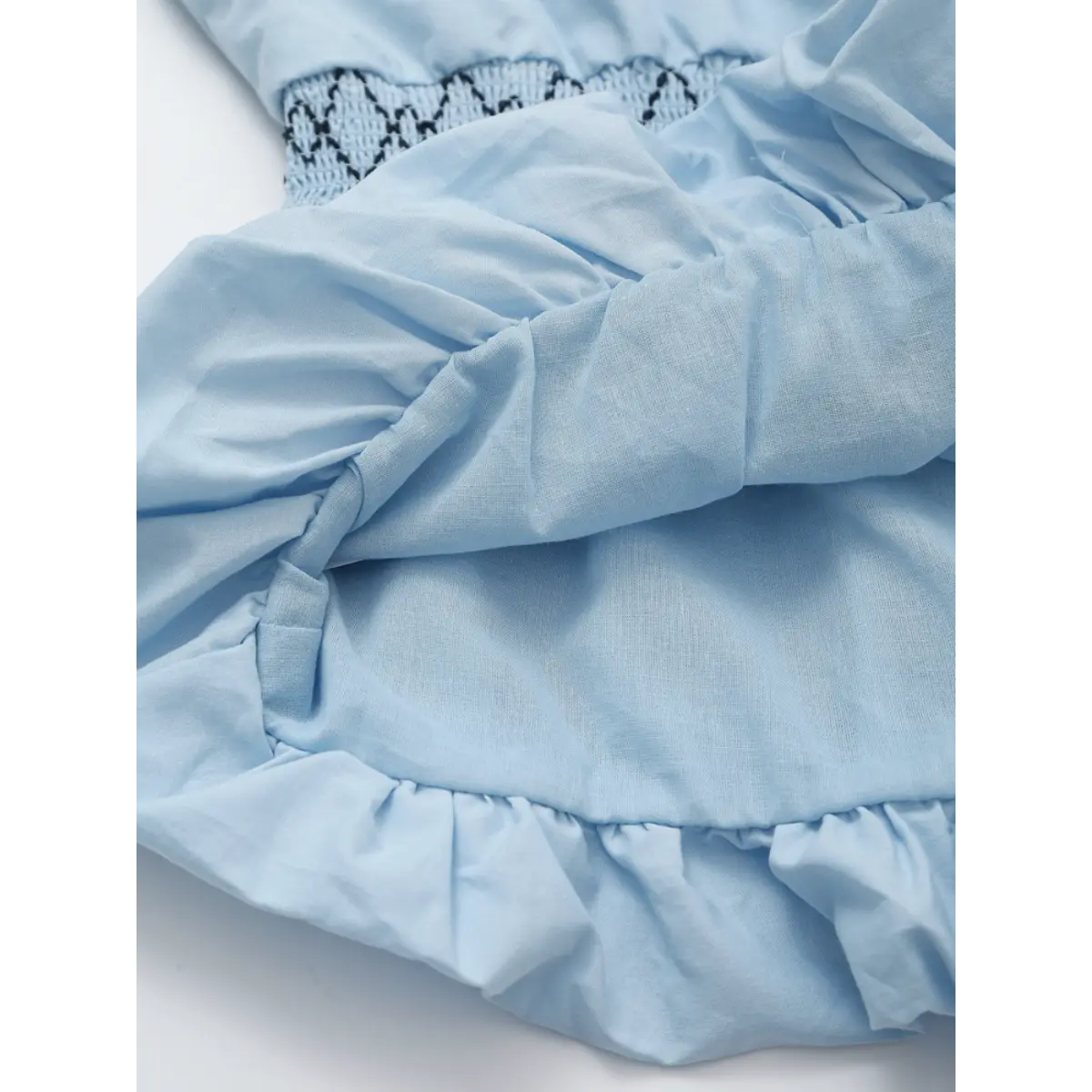Close-up of the ruffled peplum hem and lightweight fabric texture on the light blue strapless top