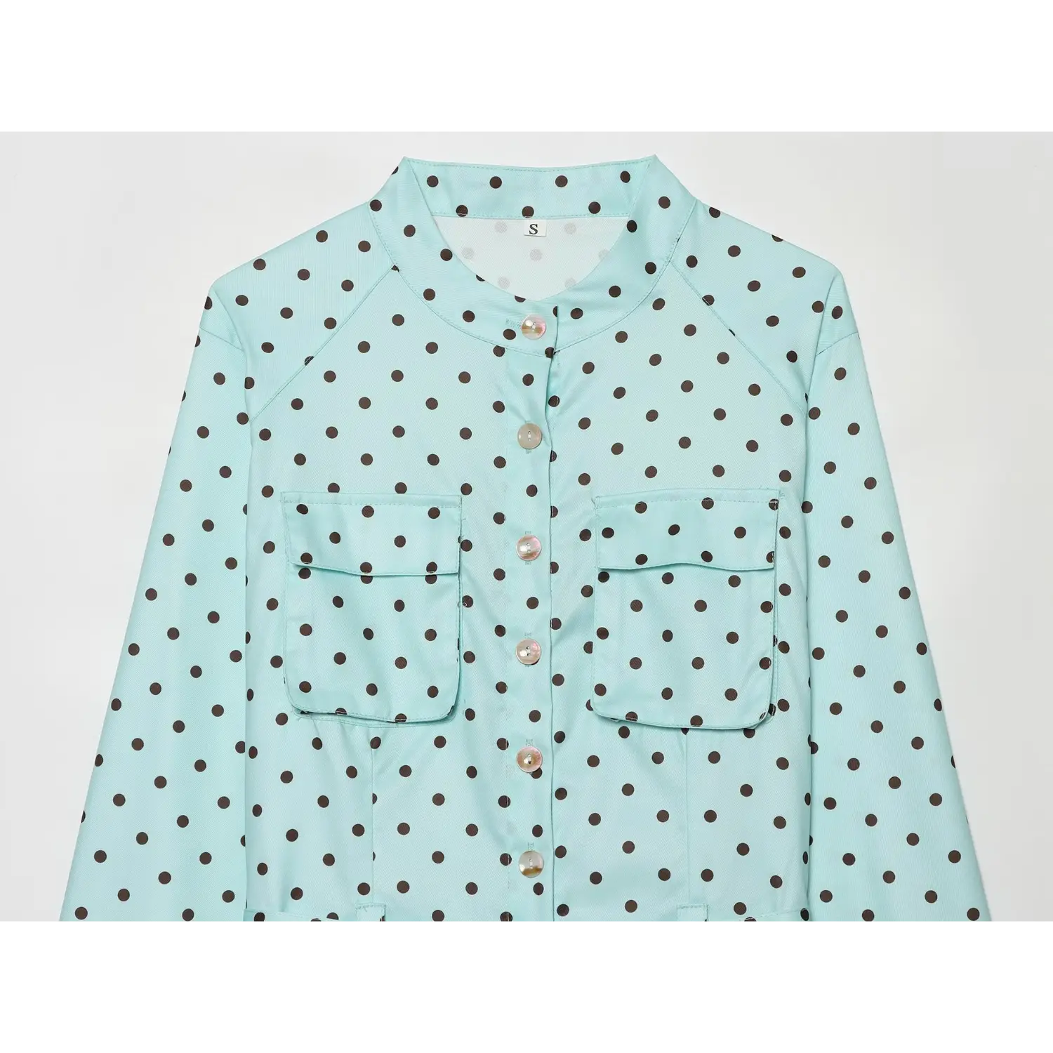 Closeup mandarin stand neck, raglan shoulder seams, dual rectangular patch chest pockets, vertical shell button placket