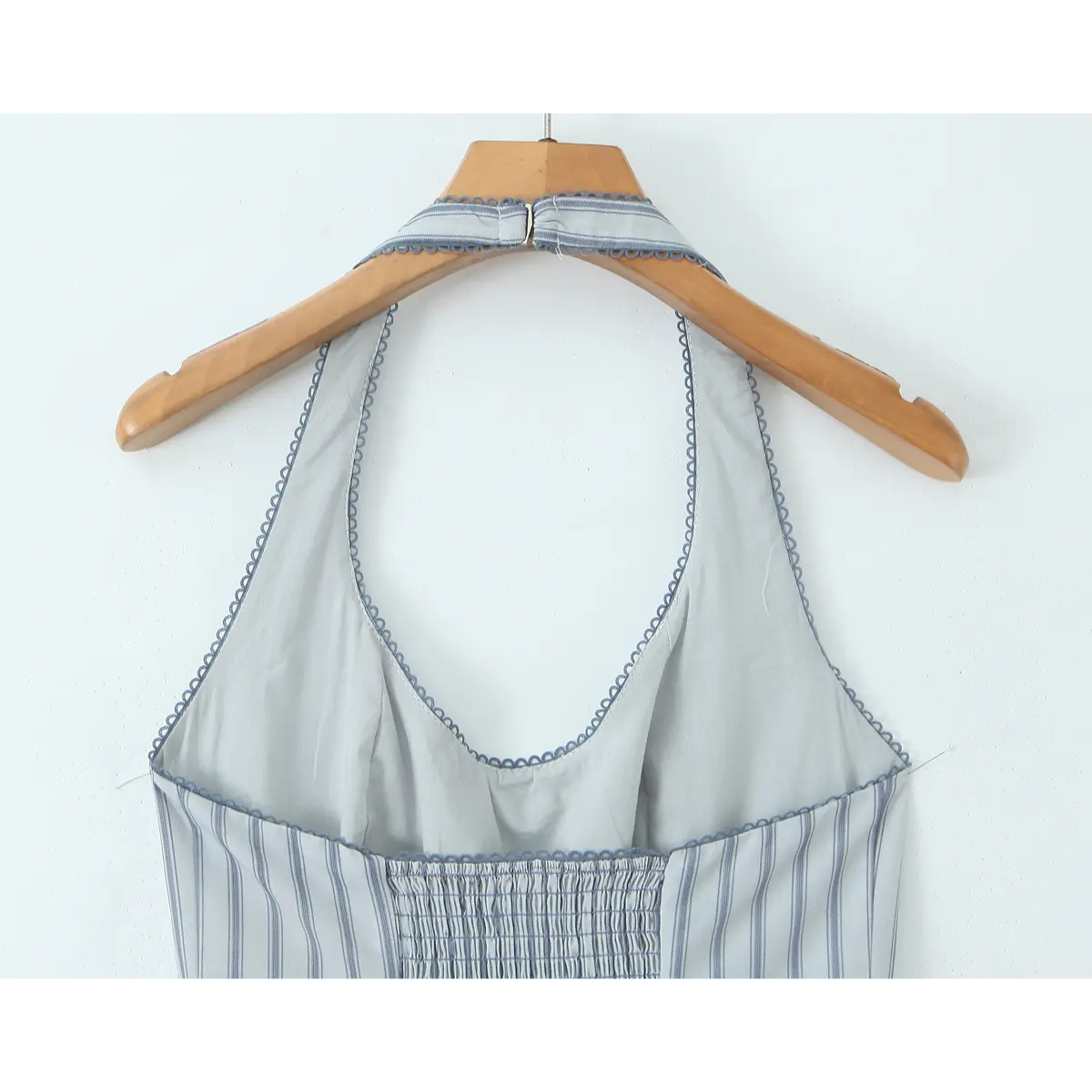 Close-up of the halter neckline closure and smocked back panel on the light blue striped dress.