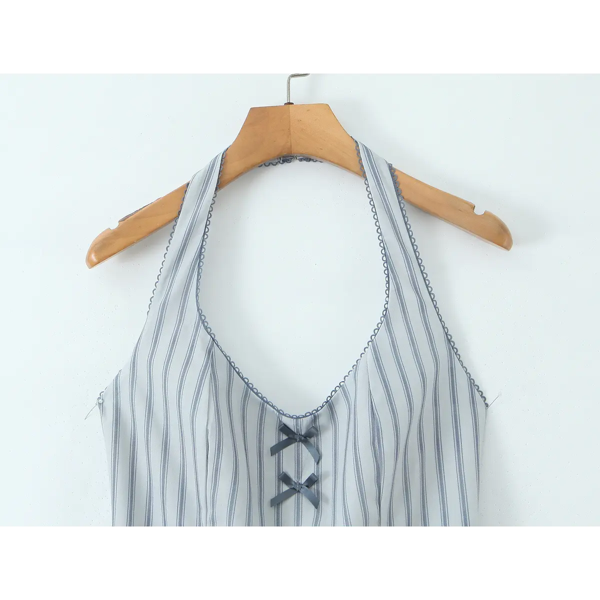 Close-up view of the light blue striped halter dress, showing the scalloped trim on the neckline and halter straps, plus the gray ribbon bows on the bodice.