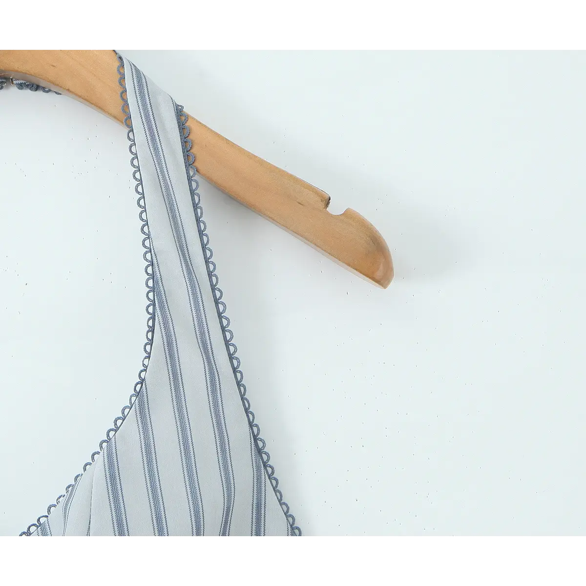 Close-up of the halter strap and scalloped trim on the light blue striped dress, showing the pattern and edge finish.
