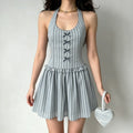 Model wearing a light blue striped halter dress with gray ribbon bows on the bodice, gathered waist ruffle, and flared skirt, holding a matching heart-shaped handbag.