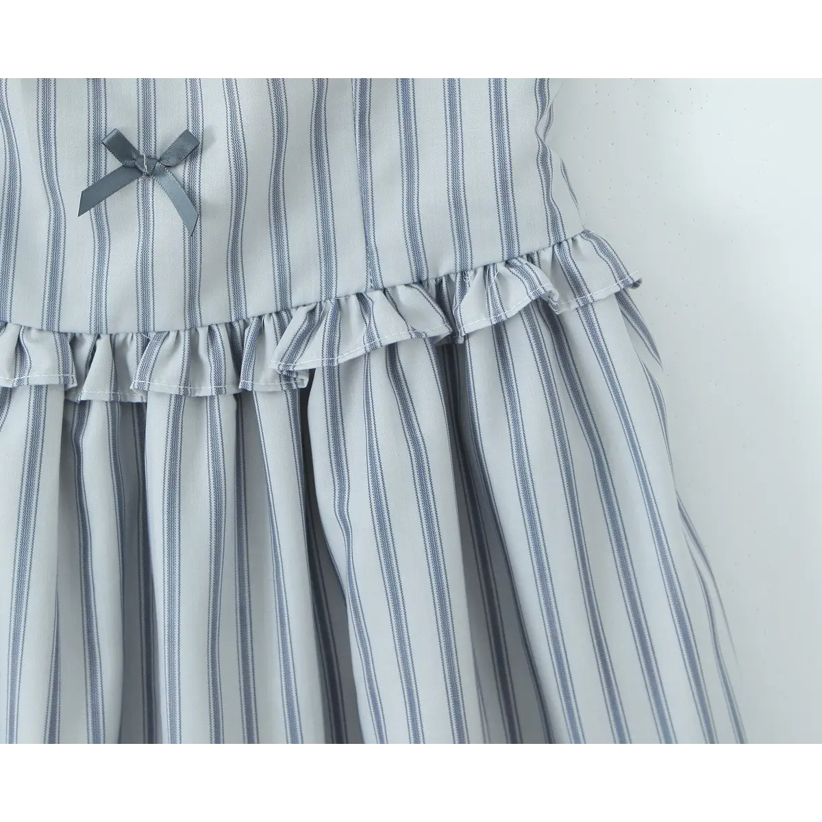  Close-up detail of the gathered waist ruffle on the light blue striped halter dress, with a small gray ribbon bow accent.