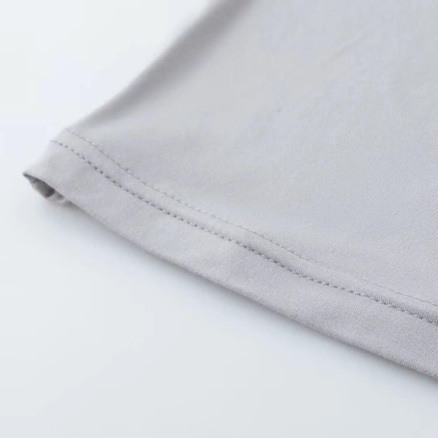 Close‑up view of bottom hem neat stitching on light gray halter crop camisole
