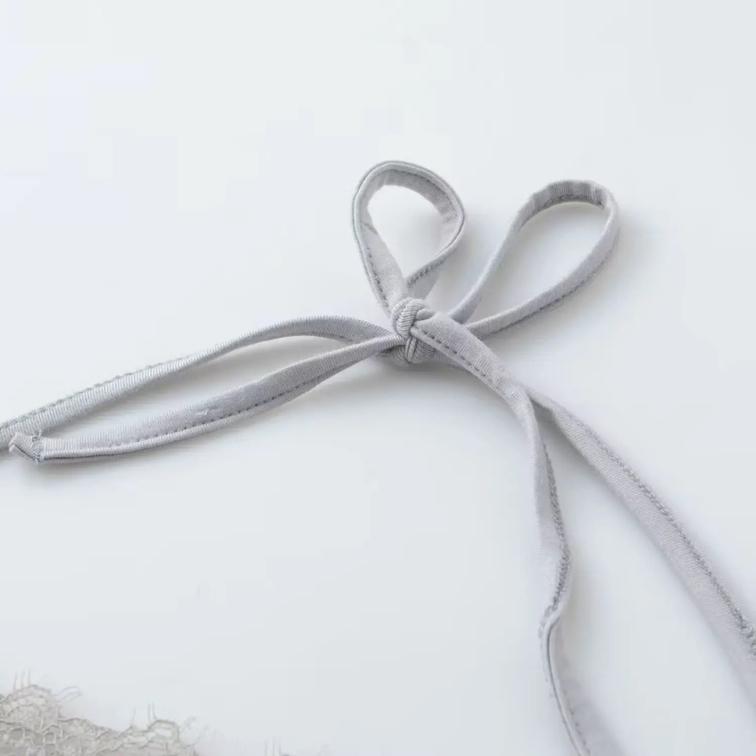 Close‑up detail of knotted halter neck tie straps on light gray camisole top